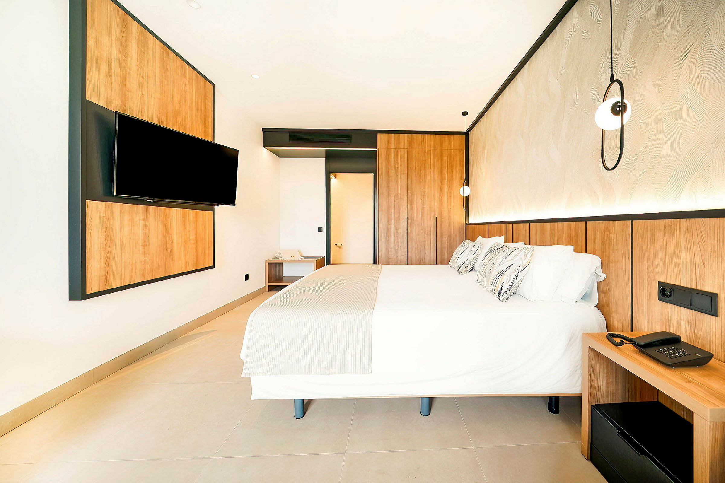 Ett hotellrum med en stor säng, träpaneler och en TV på väggen. (AI-genererad text)
