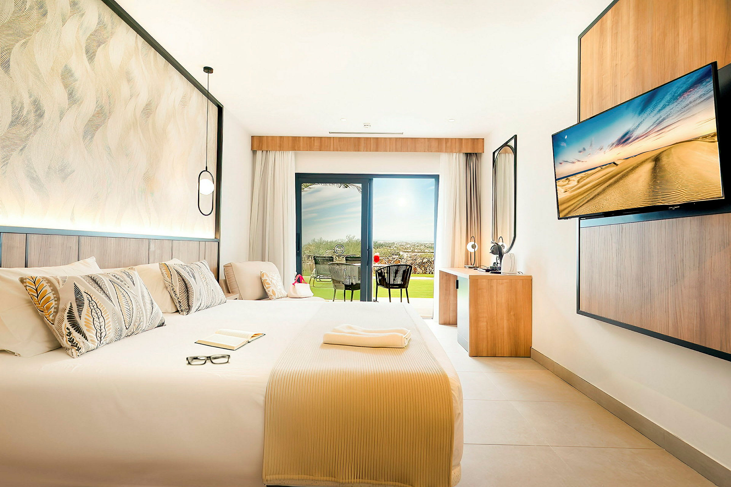 Modern hotellrum med stor säng, skrivbord och utsikt mot en terrass. (AI-genererad text)