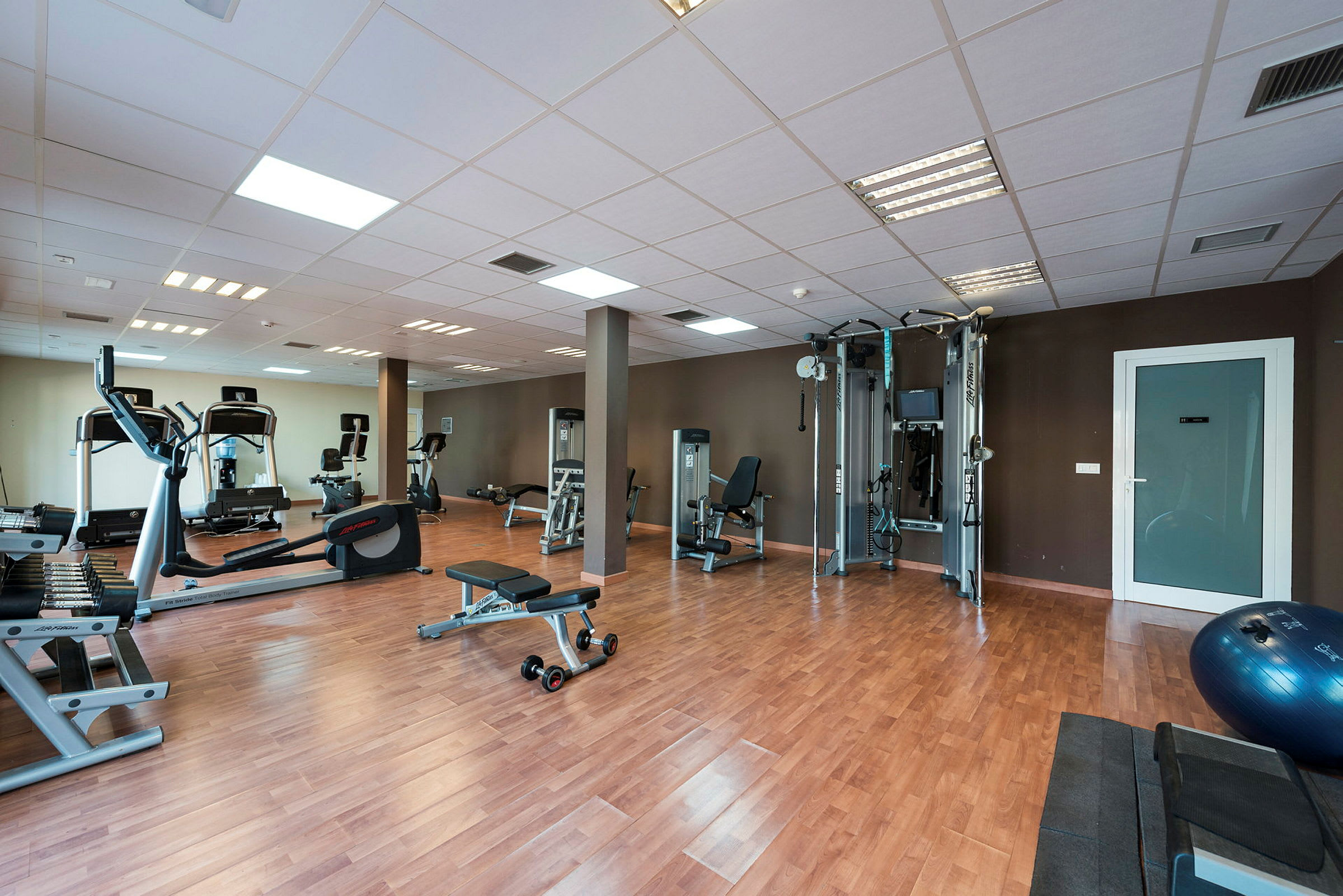 Ett modernt gym med träningsutrustning och träpanelgolv. (AI-genererad text)