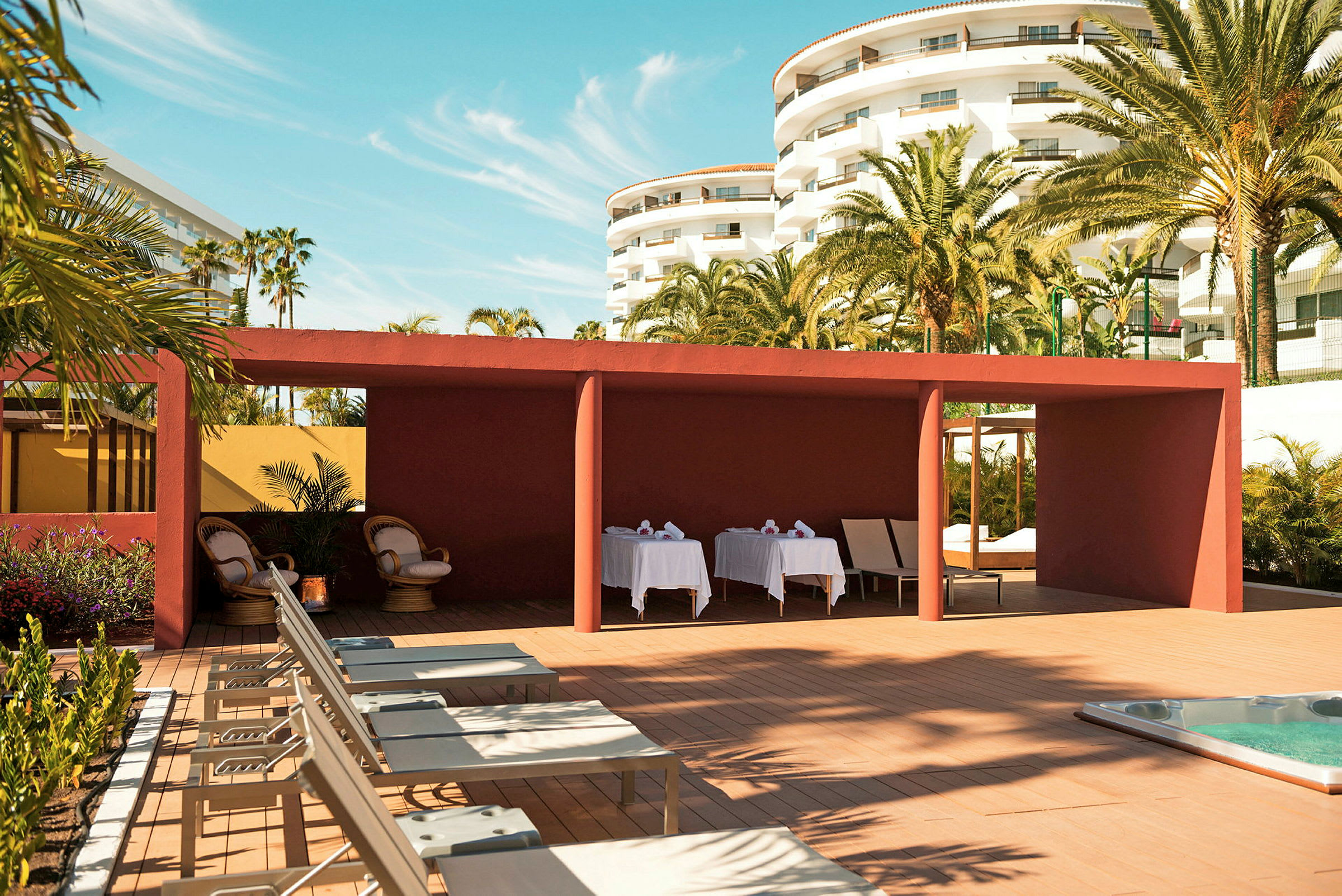 Solstolar och en röd pergola vid ett hotell med palmer. (AI-genererad text)