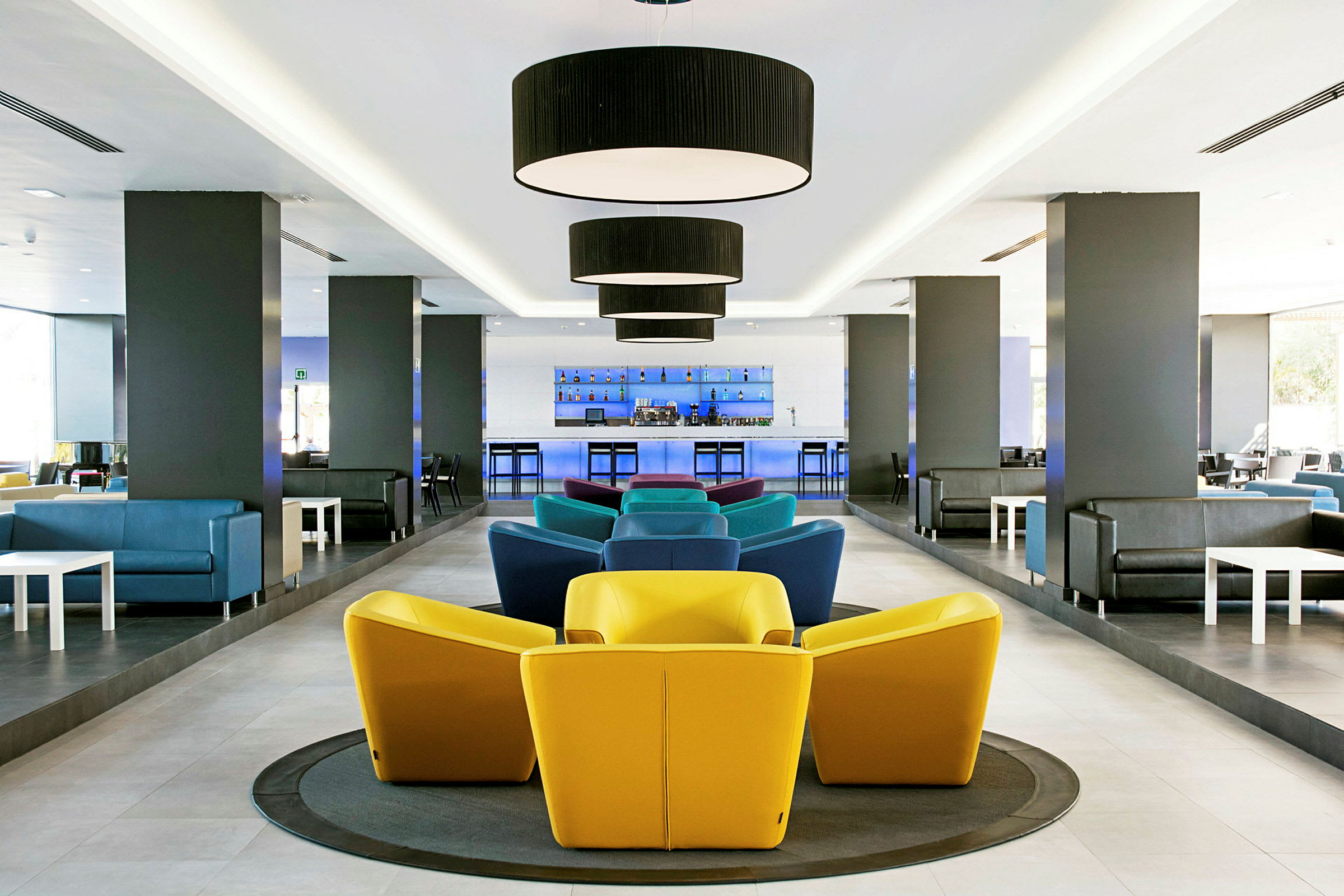 Modern lounge med färgglada stolar och bar i bakgrunden. (AI-genererad text)