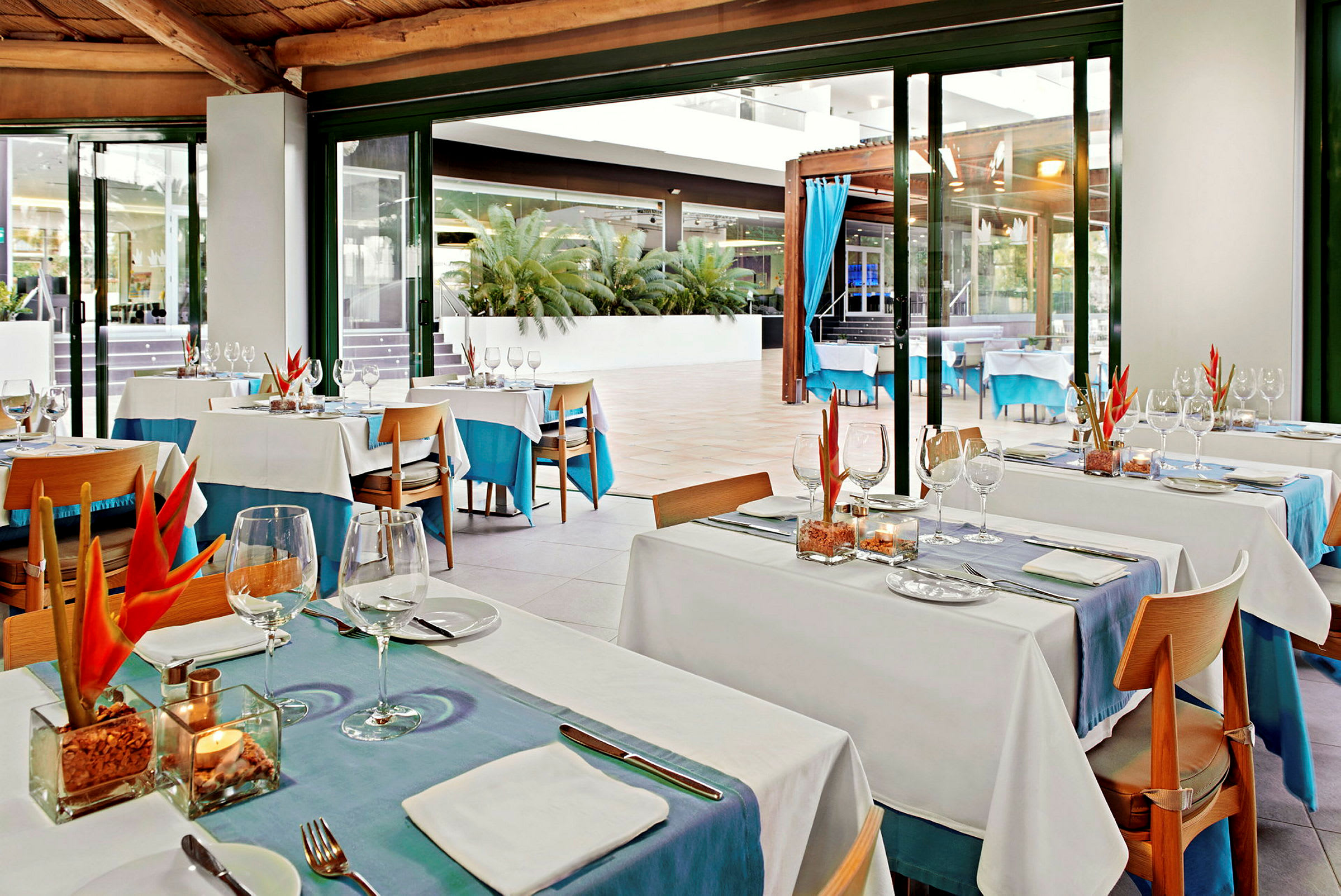 Restaurangområde med dukade bord, glas och tropisk dekoration. (AI-genererad text)