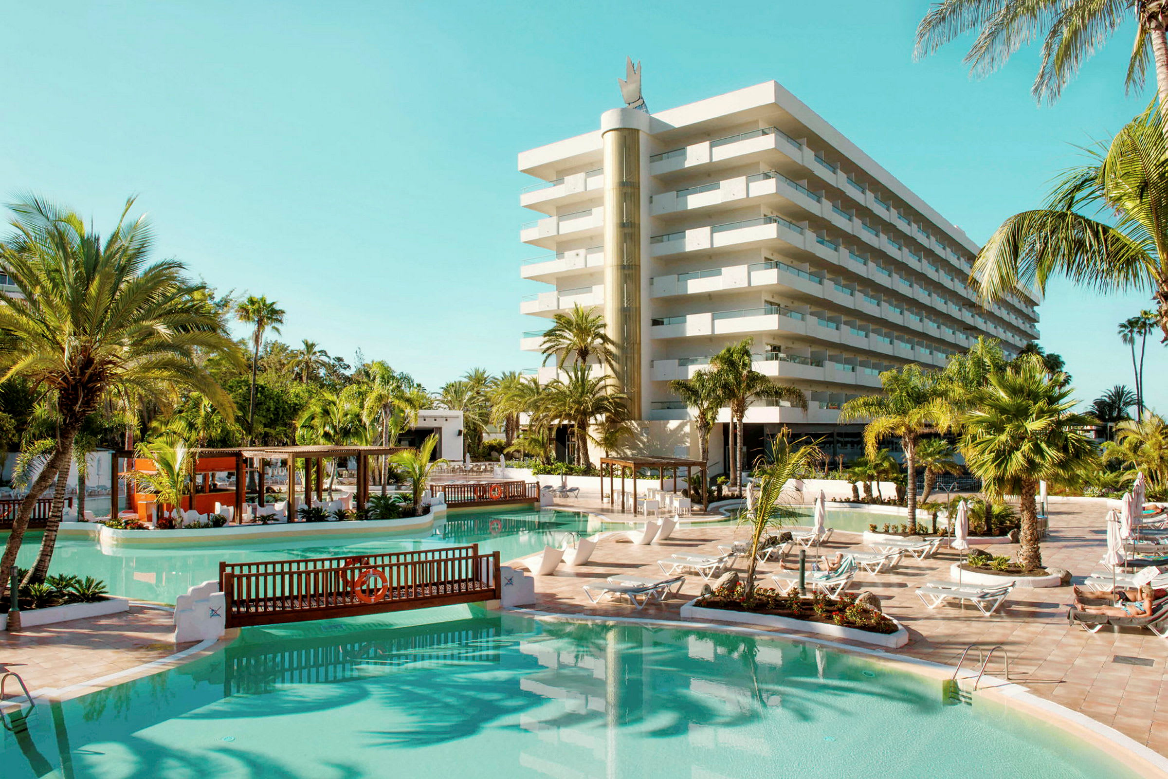 Hotell med poolområde, solstolar och palmer. (AI-genererad text)