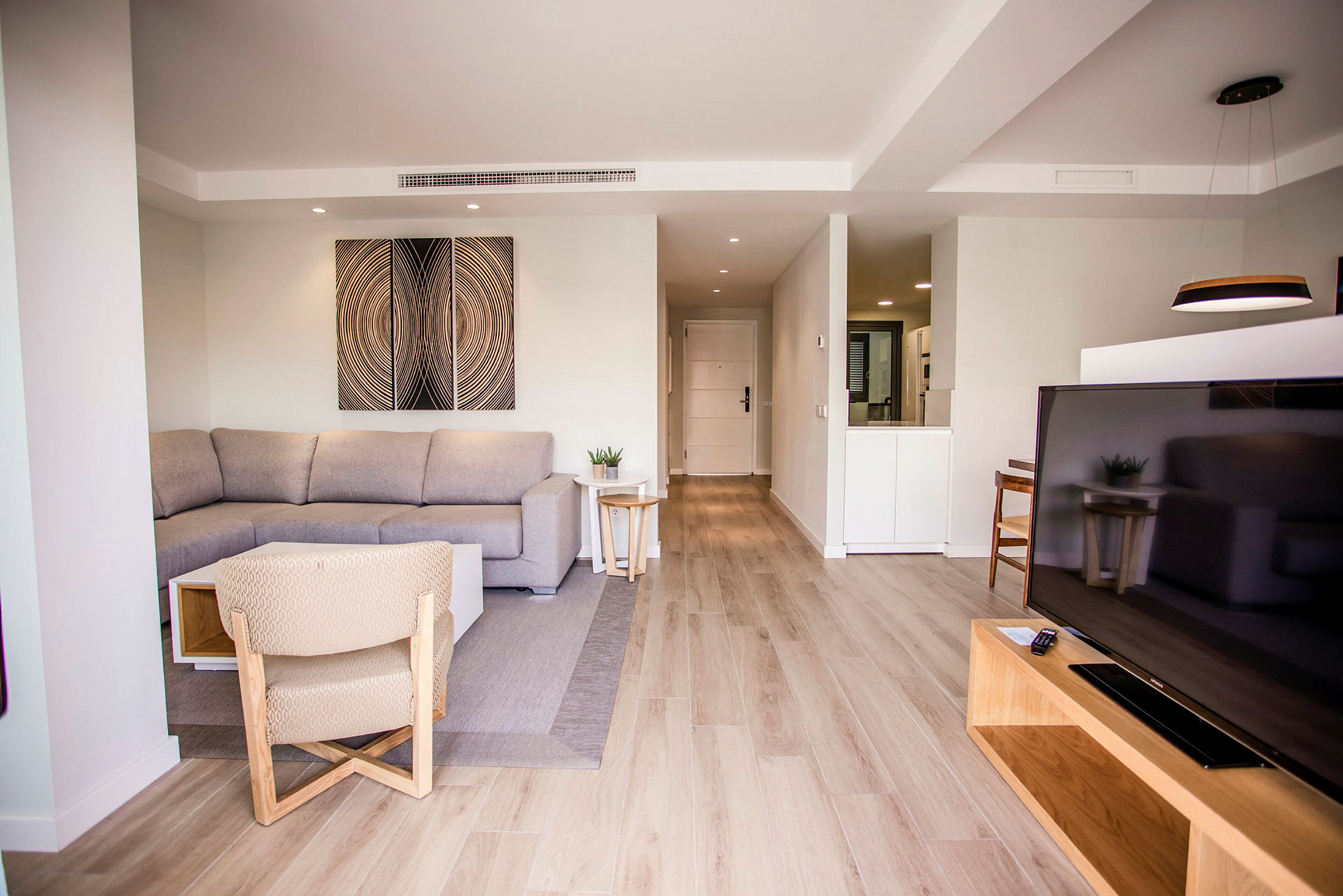En modern vardagsrumsinredning med soffa, TV och ljusa trädetaljer. (AI-genererad text)