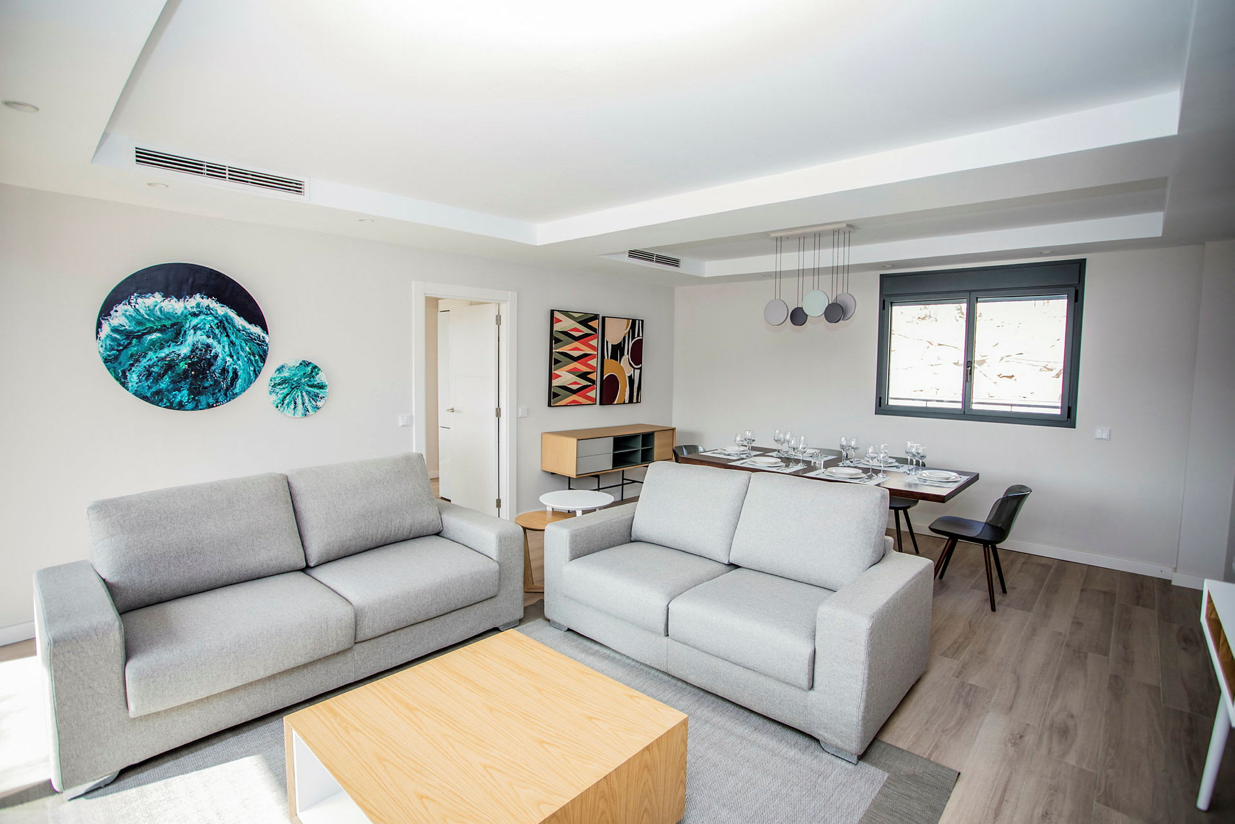 En modern möblerad sittplats med två soffor och ett matbord i bakgrunden. (AI-genererad text)