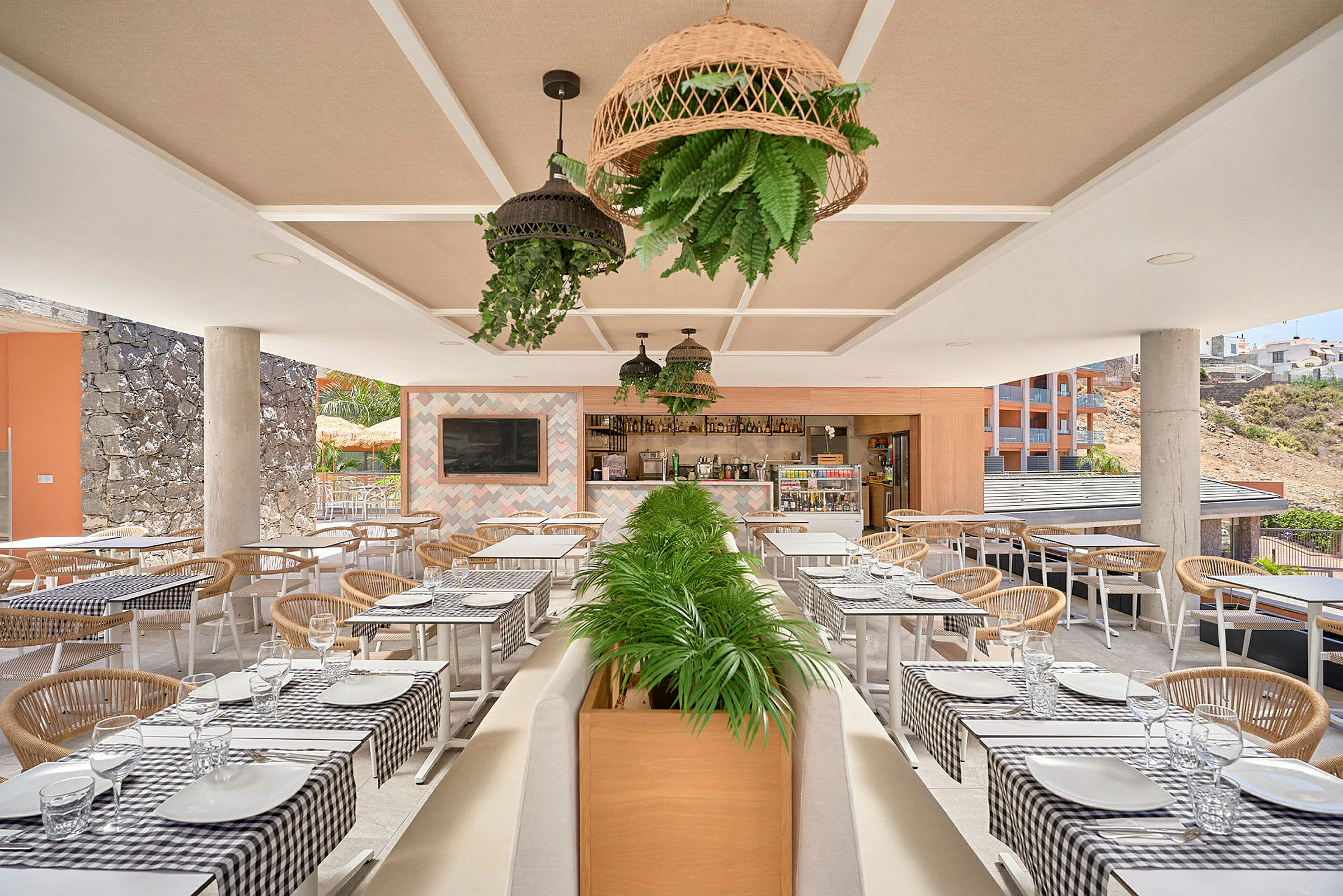 Utomhusrestaurang med dukade bord och dekorerade växter. (AI-genererad text)