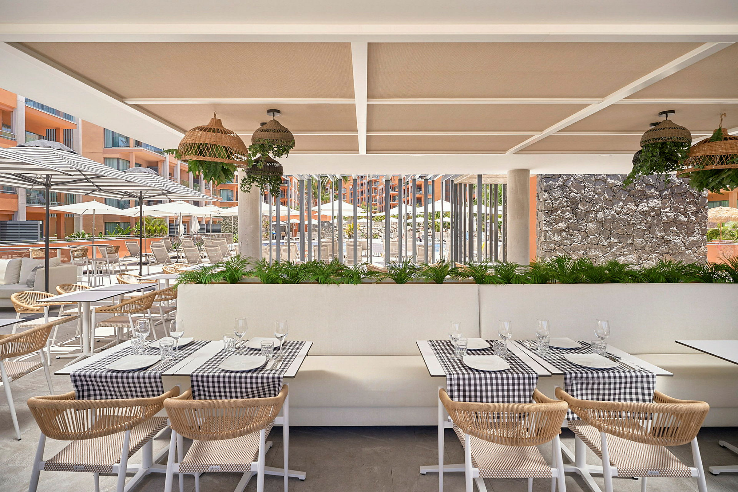 En restaurang med dukade bord och utsikt över en poolområde med solstolar och parasoller. (AI-genererad text)