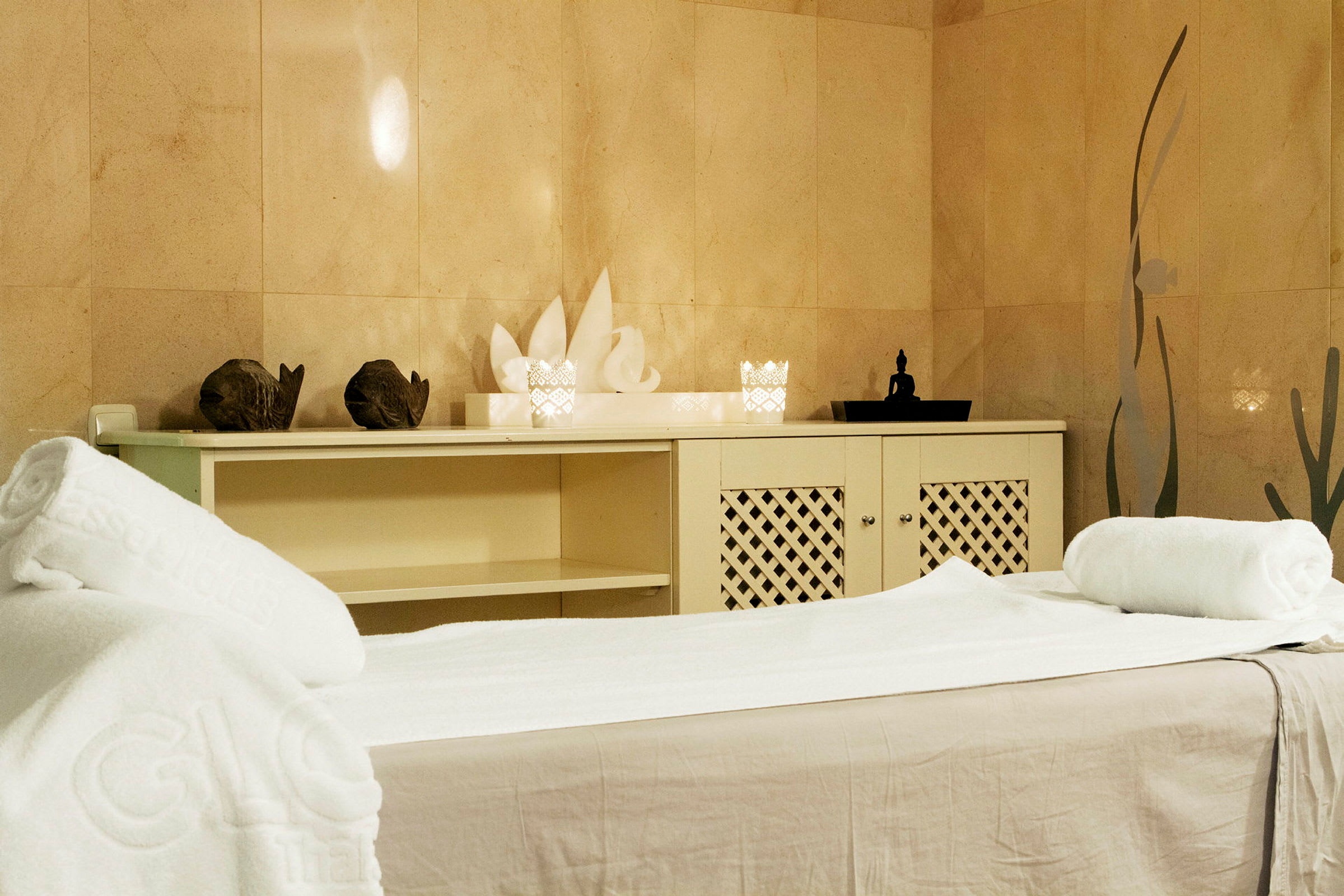 Ett spa-rum med massagebänk, handdukar och dekorationer. (AI-genererad text)