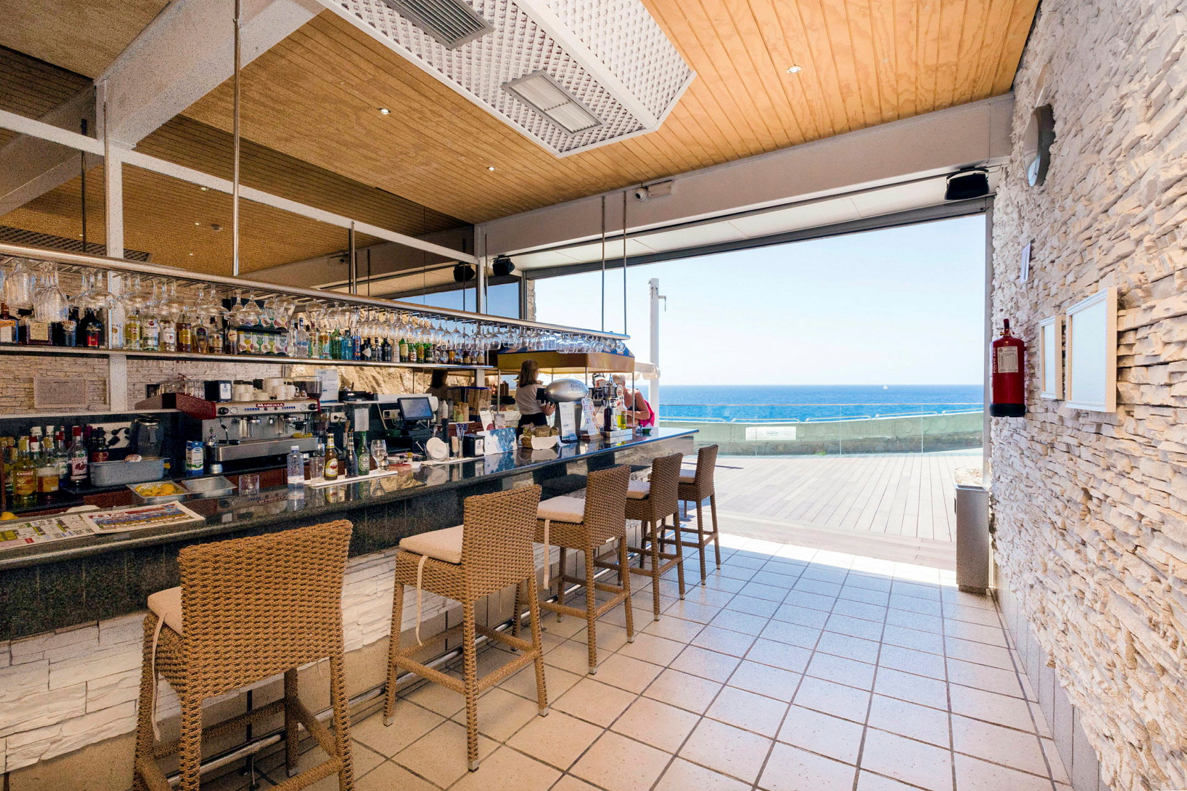 En bar med höga stolar och utsikt över havet. (AI-genererad text)