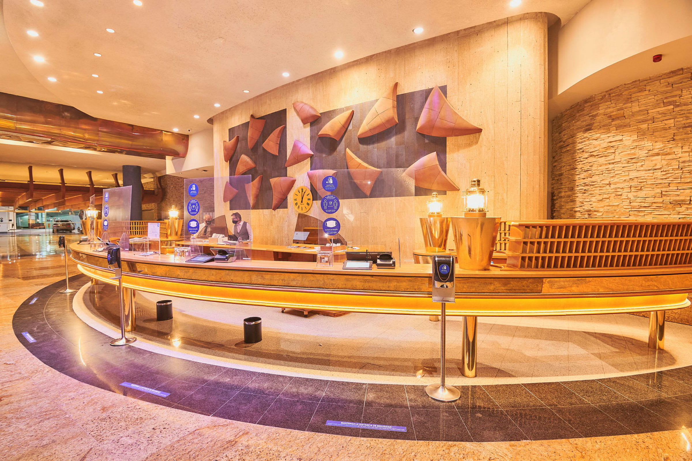 Hotellets reception med kurvad disk, dekorativa inslag och en anställd vid arbetsstationen. (AI-genererad text)