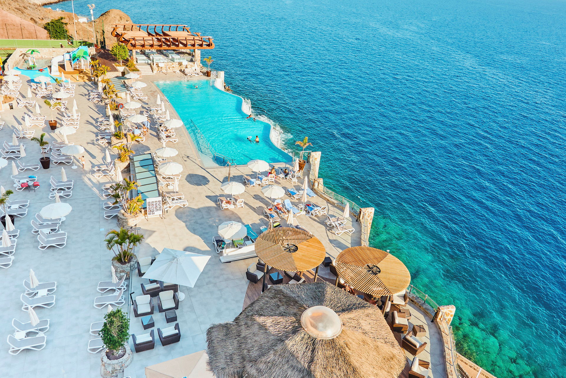 Utsikt över en pool och solstolar vid havet. (AI-genererad text)