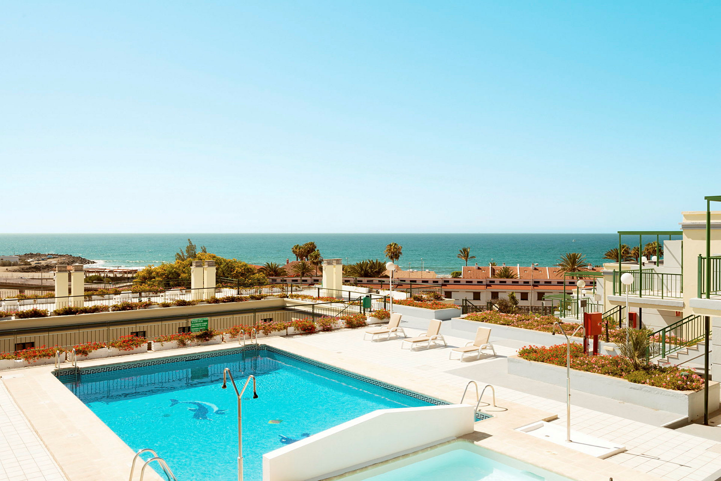 Bild på en pool och solterrass med havet i bakgrunden. (AI-genererad text)