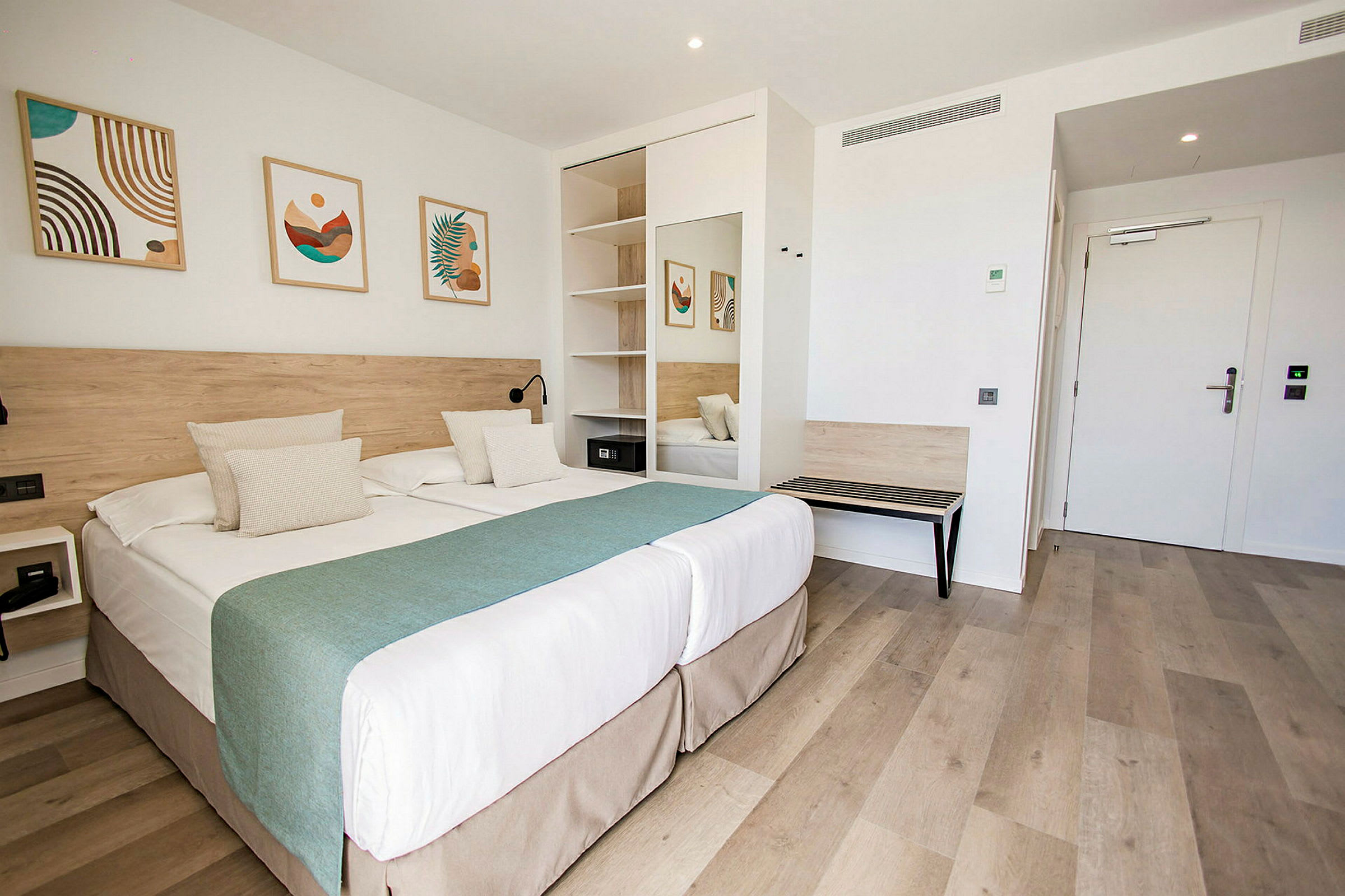 Ett hotellrum med dubbelsäng, väggdekorationer och en garderob. (AI-genererad text)