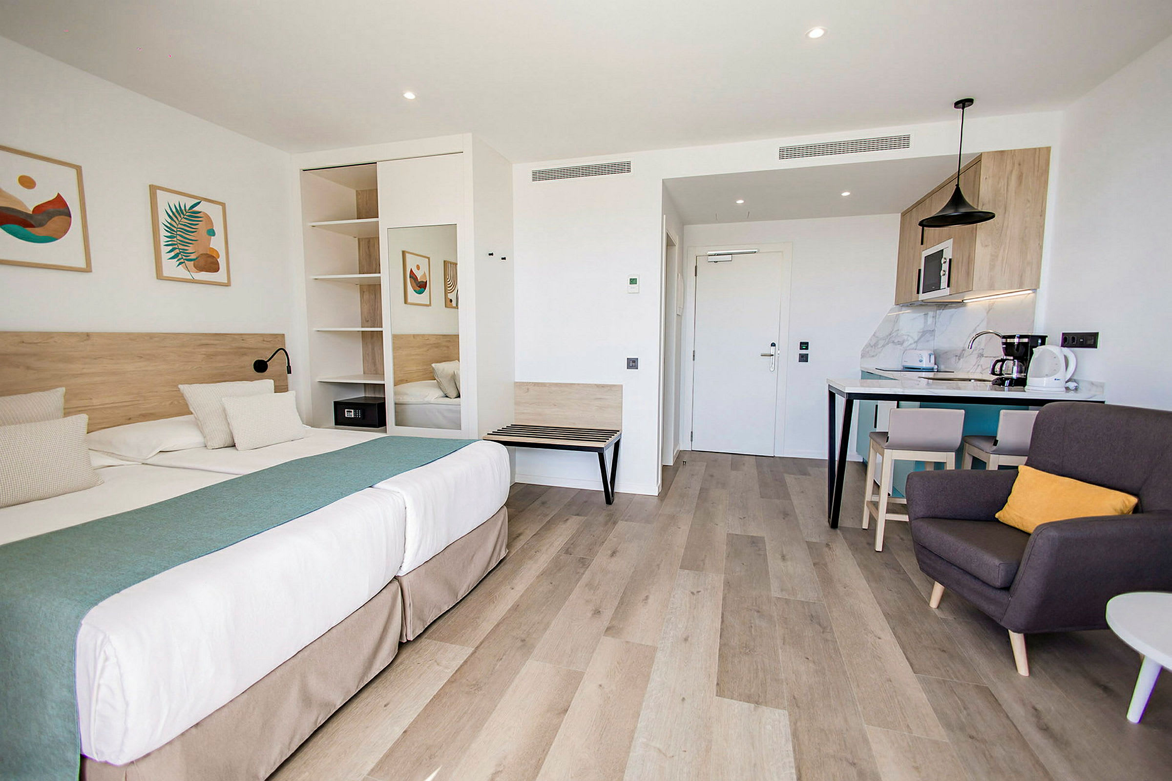 En modern hotellstudio med dubbelsäng, sittgrupp och köksdel. (AI-genererad text)