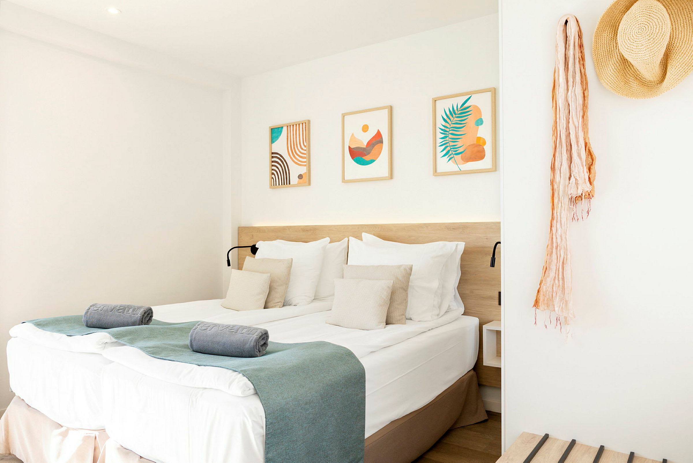 Ett hotellrum med en dubbelsäng, dekorerade kuddar och konstverk på väggen. (AI-genererad text)