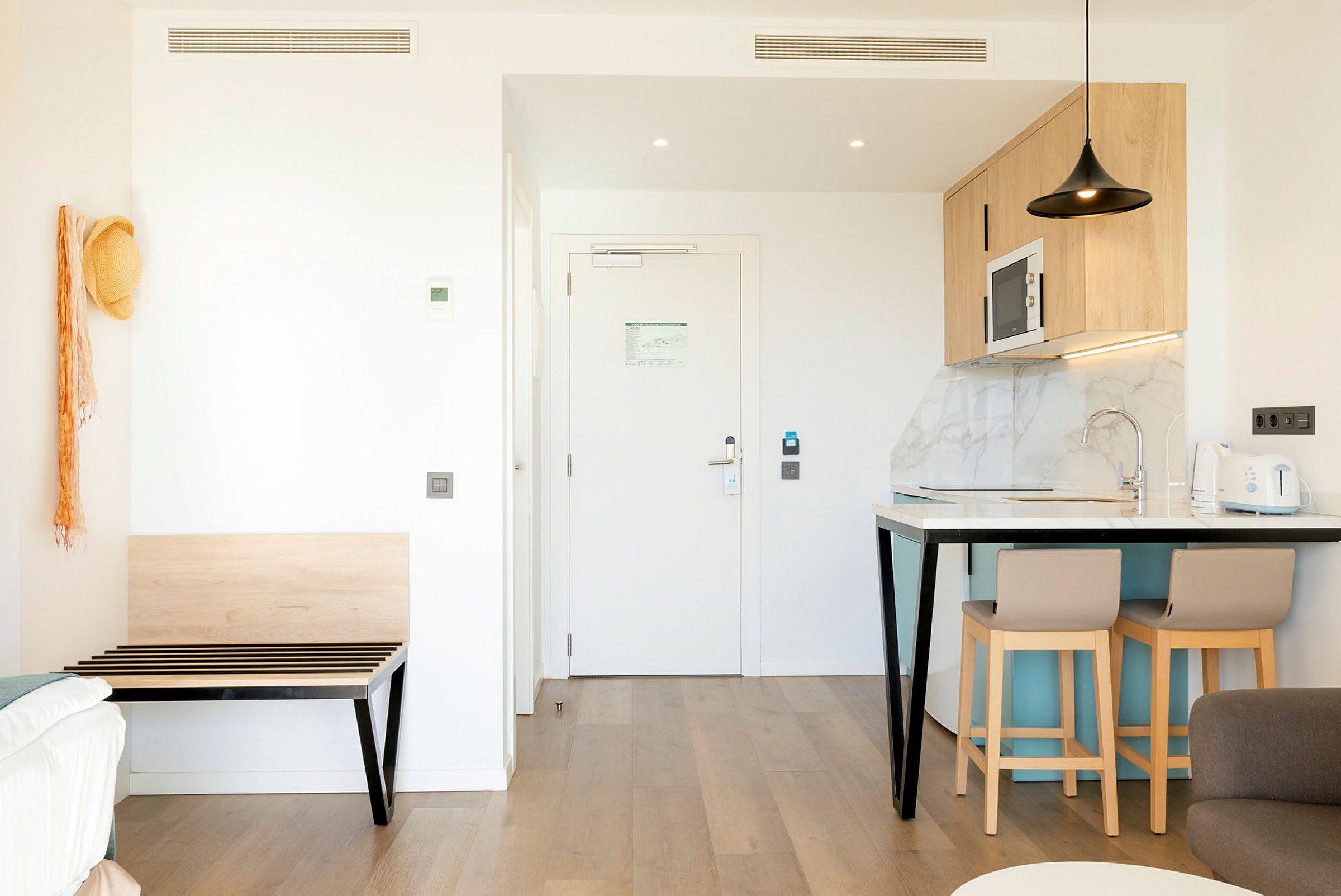 Bild av ett modernt hotellrum med köksdel och entré. (AI-genererad text)
