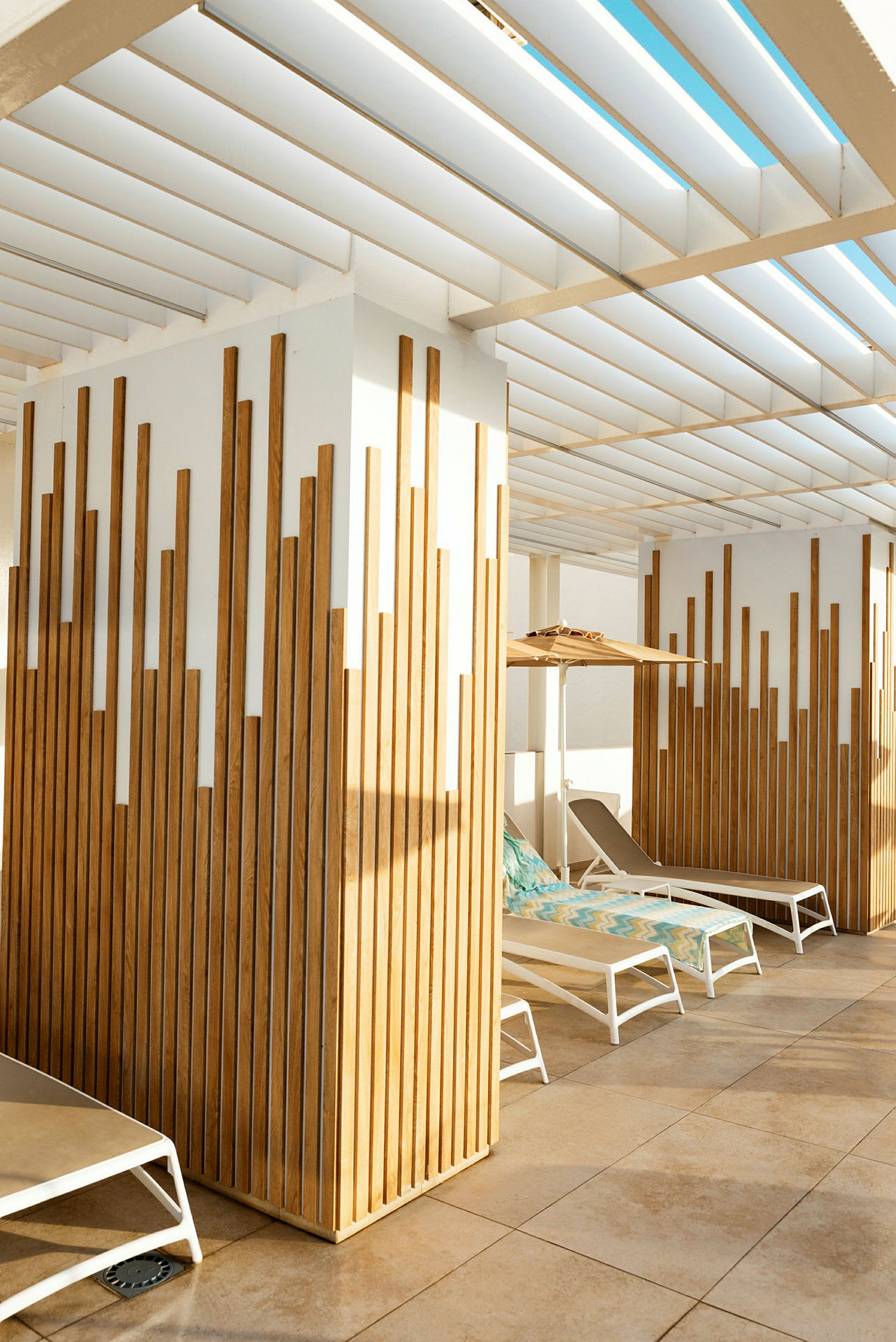 Utemiljö med solsängar under en pergola och träpaneler. (AI-genererad text)