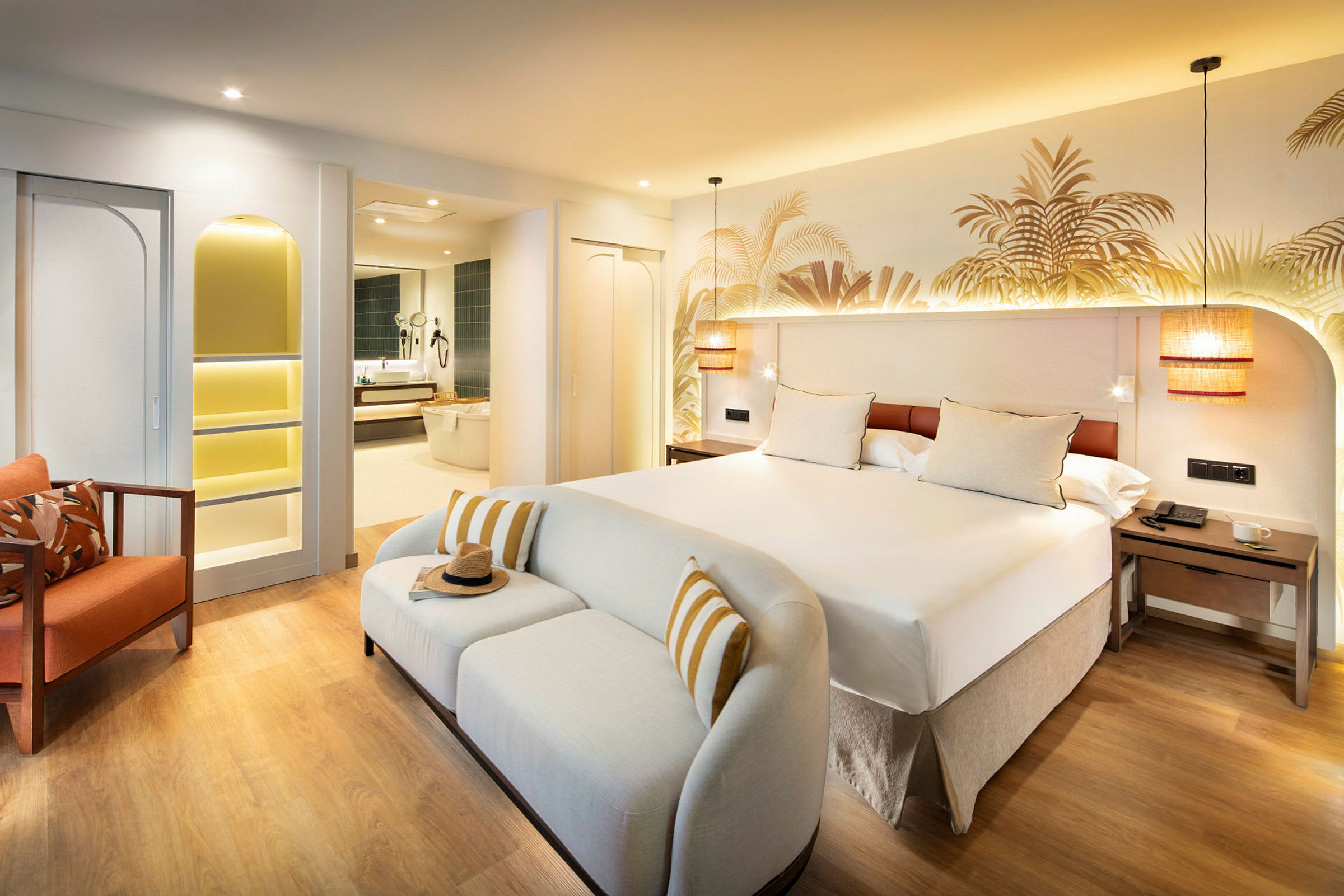 Ett hotellrum med en stor säng, en vit soffa och en orange stol, med ett badrum synligt i bakgrunden. (AI-genererad text)
