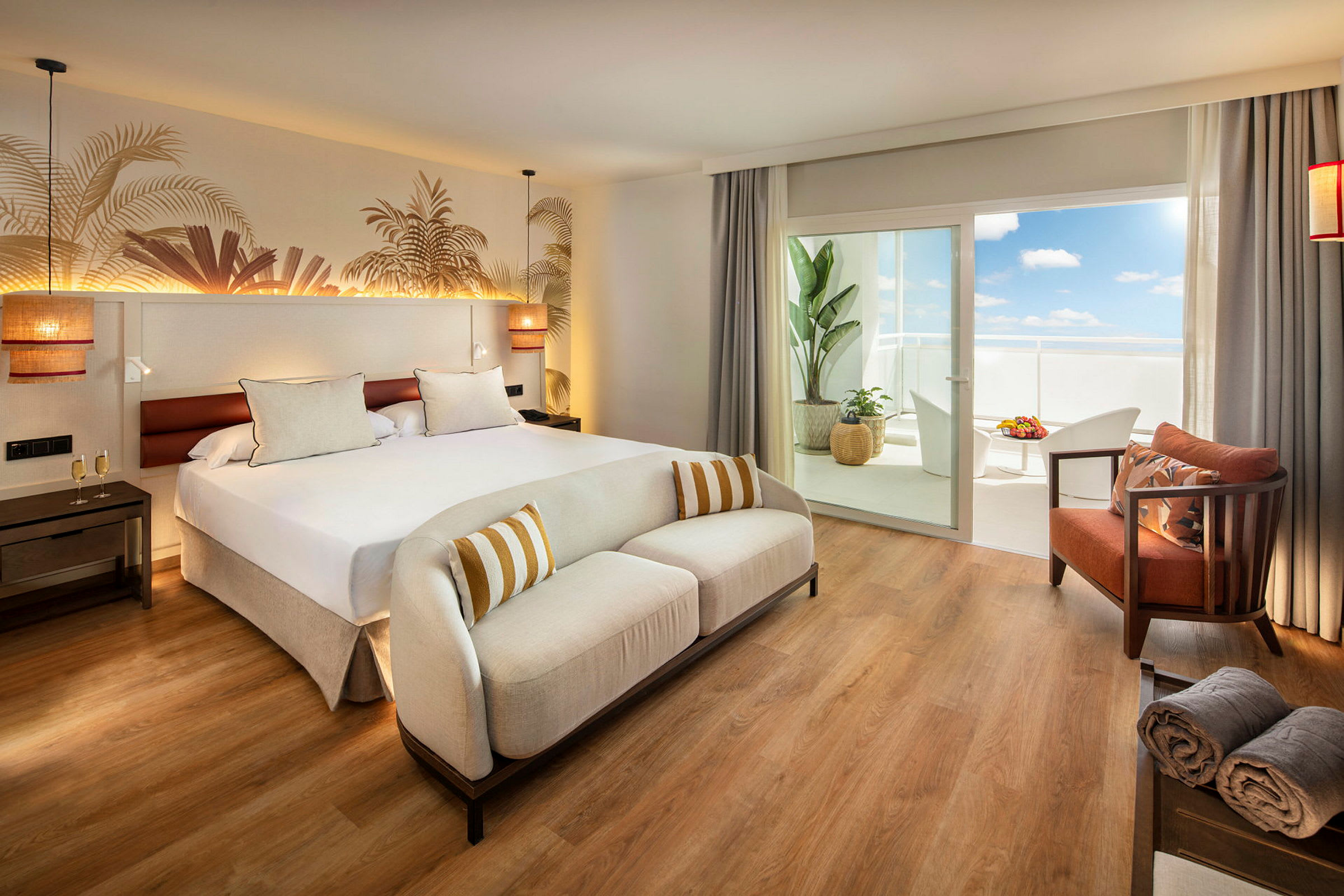Ett hotellrum med en stor säng, en vit soffa och en balkong med möbler. (AI-genererad text)
