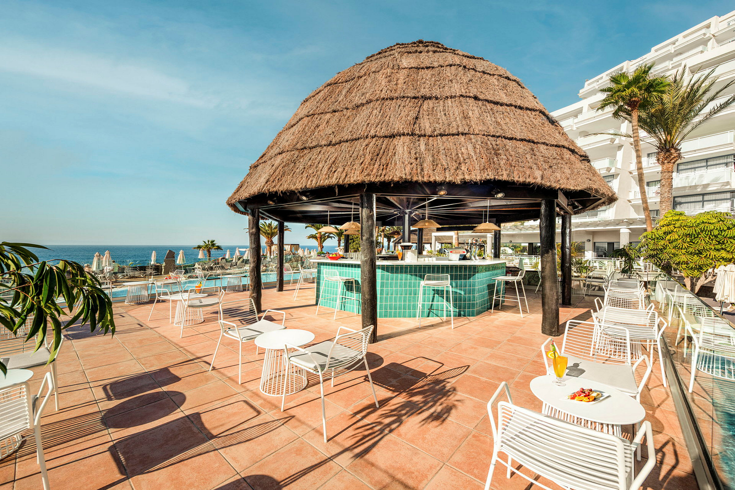 Strandbar med halmtak och sittplatser utomhus. (AI-genererad text)