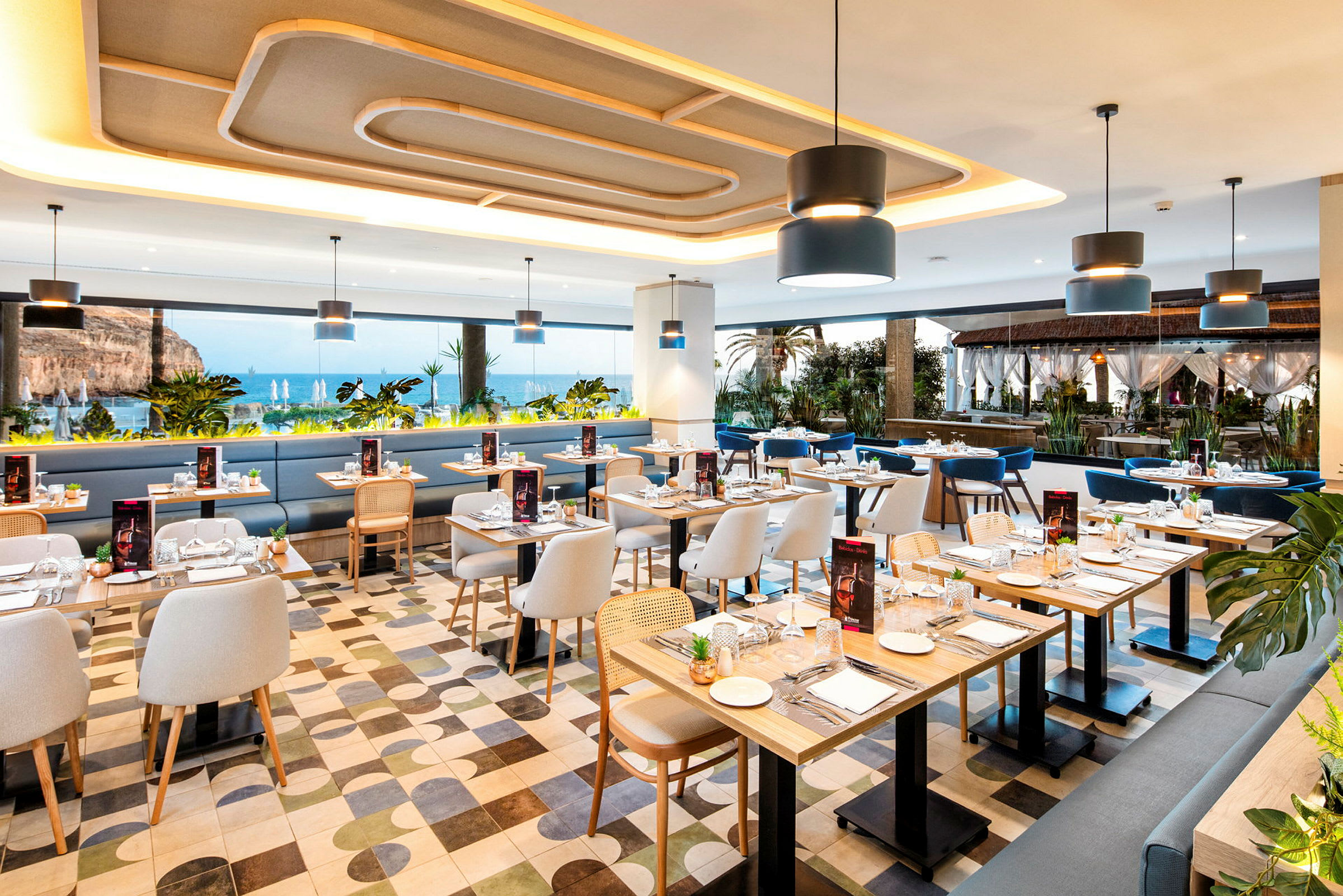 Interiör av en restaurang med havsutsikt, moderna möbler och bord uppdukade. (AI-genererad text)