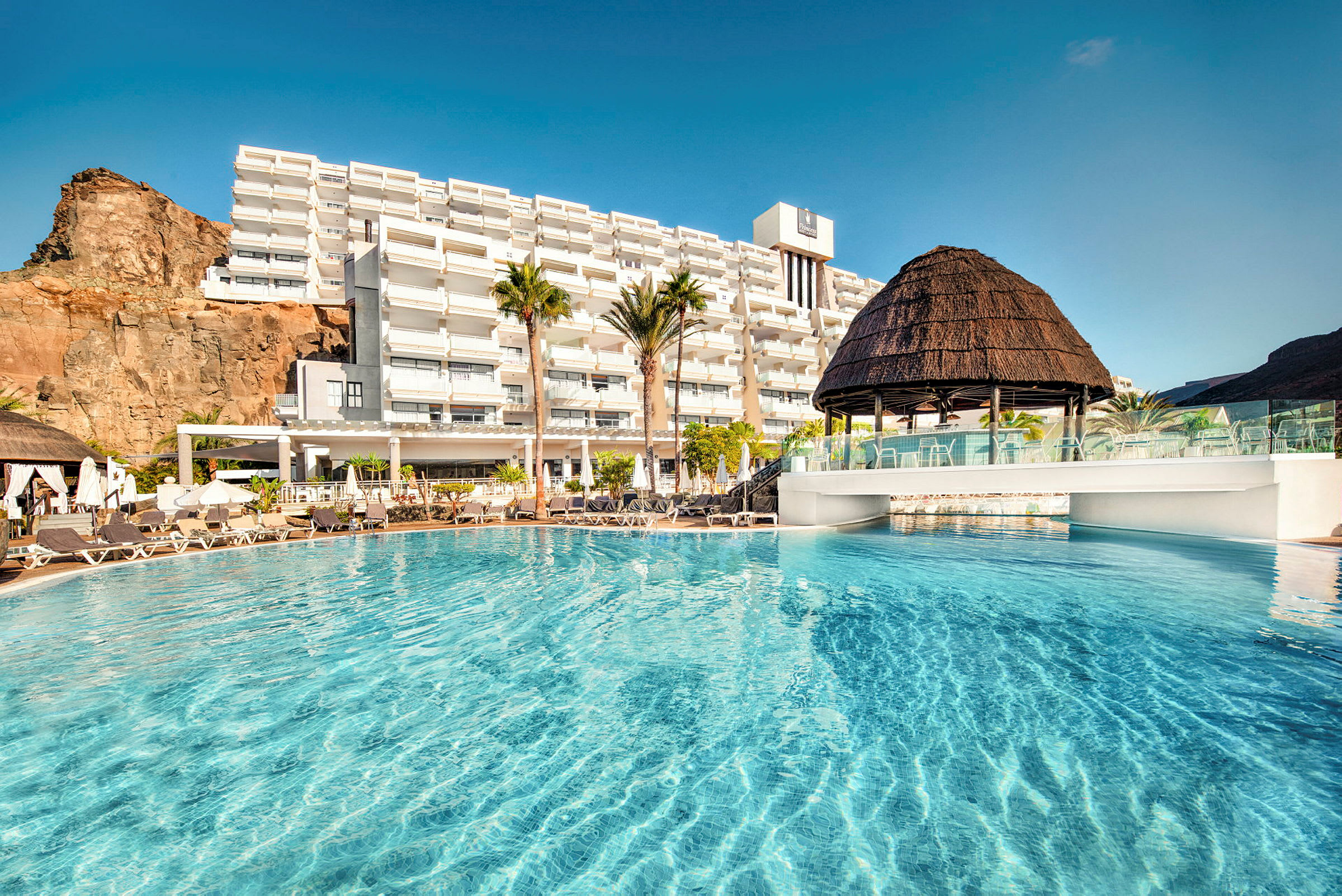Hotell med stor pool och solstolar utomhus. (AI-genererad text)