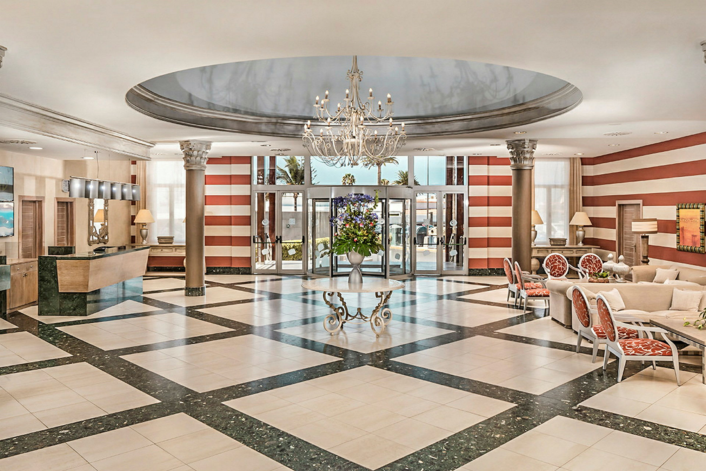 Ett elegant hotellobbyområde med en ljuskrona, marmorgolv, reception till vänster och sittplatser till höger. (AI-genererad text)