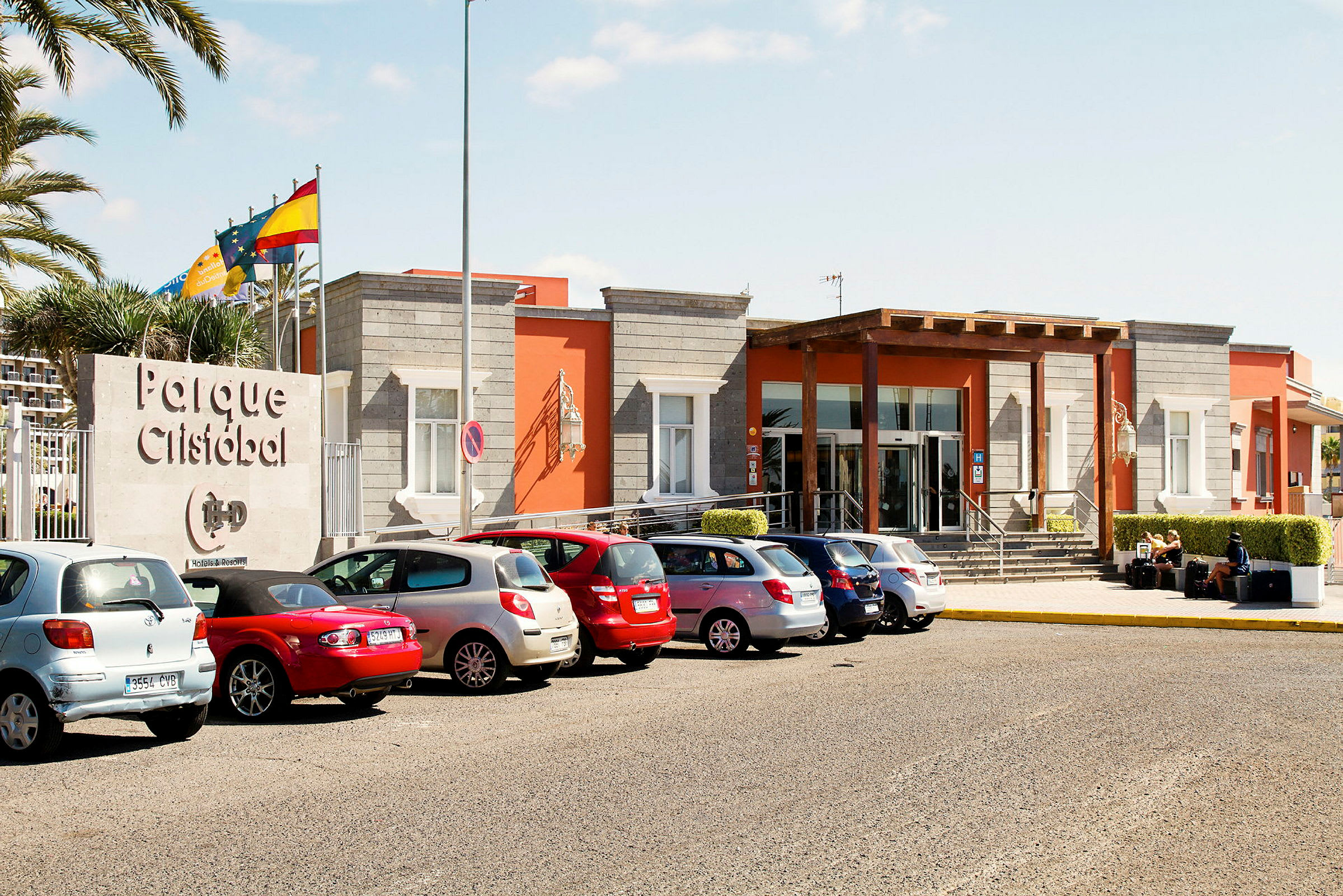 Entré till en byggnad med texten "Parque Cristóbal", omgiven av parkerade bilar. (AI-genererad text)