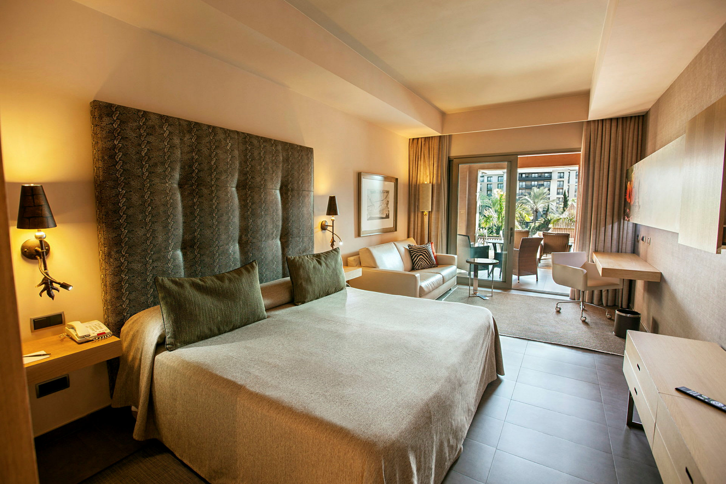 Ett hotellrum med en stor säng, soffa och skrivbord. Det finns även en balkong med utsikt. (AI-genererad text)