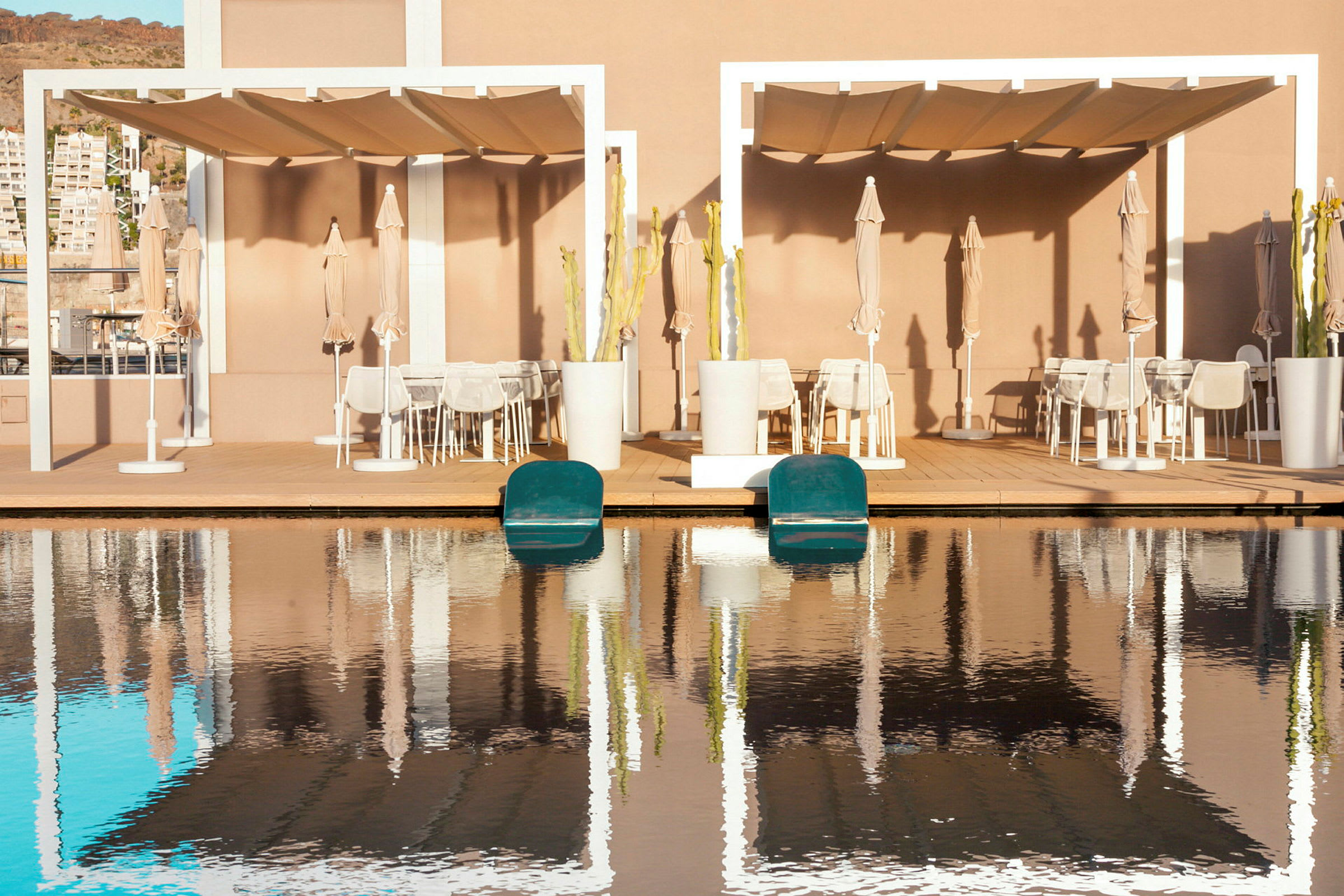 Två sittplatser under pergola nära en pool. (AI-genererad text)