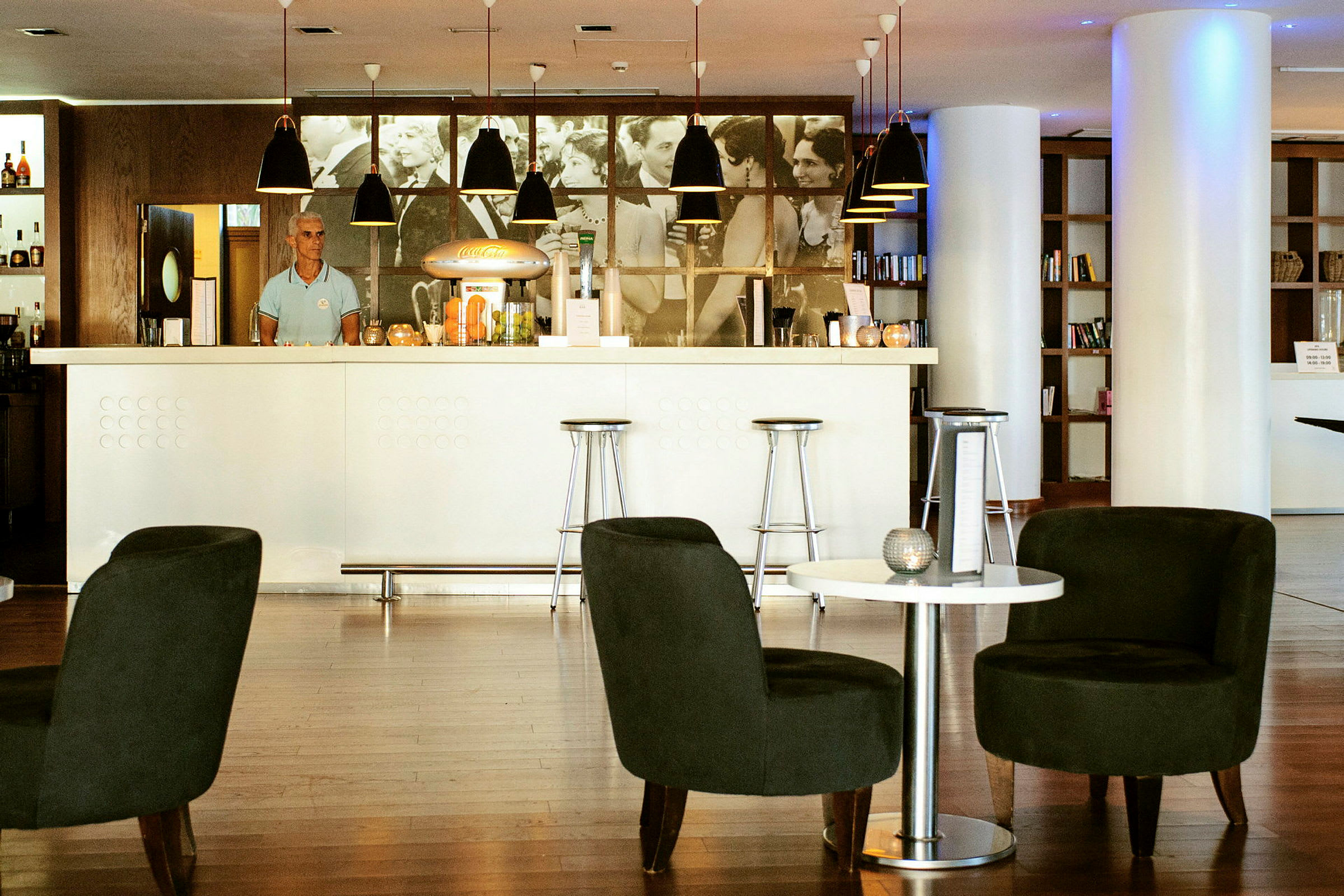 Modern bar med vita och mörka möbler samt en hylla med böcker i bakgrunden. (AI-genererad text)