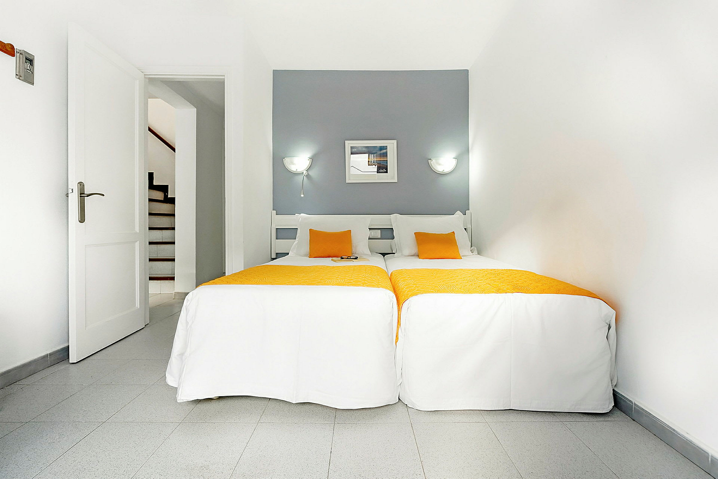 Ett hotellrum med två enkelsängar med vita sängkläder och gul dekoration. (AI-genererad text)