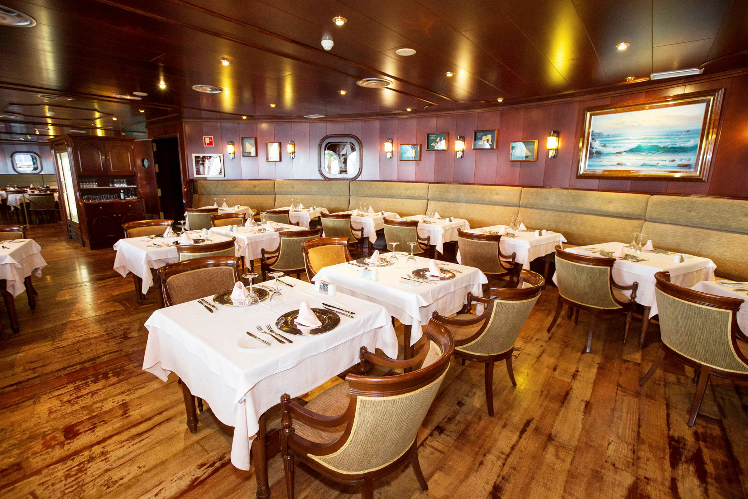 En restaurang med flera dukade bord och stolar, inredd med träpaneler och väggdekorationer. (AI-genererad text)