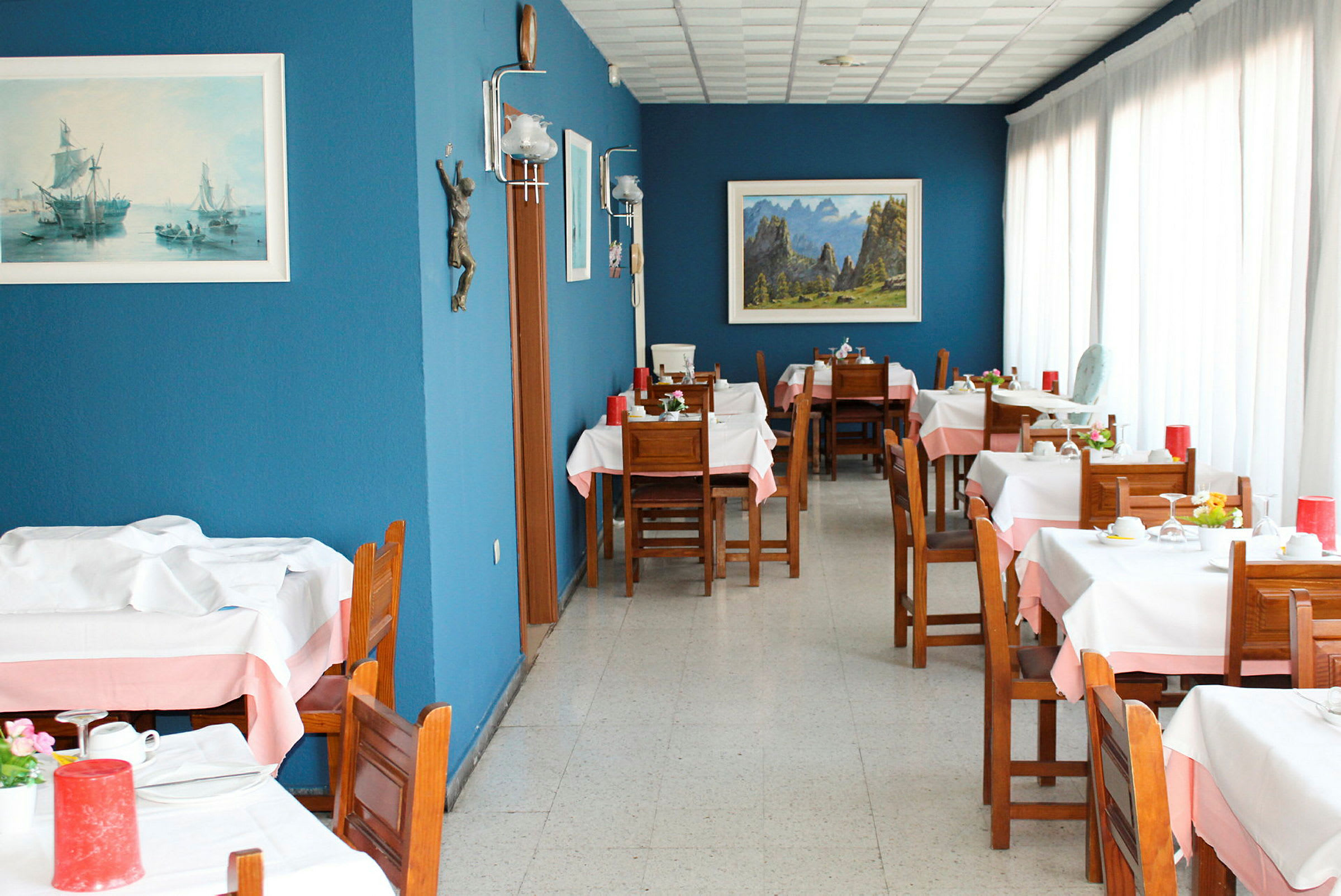 En restaurang med träbord och stolar, blå väggar samt dekorationer och tavlor. (AI-genererad text)