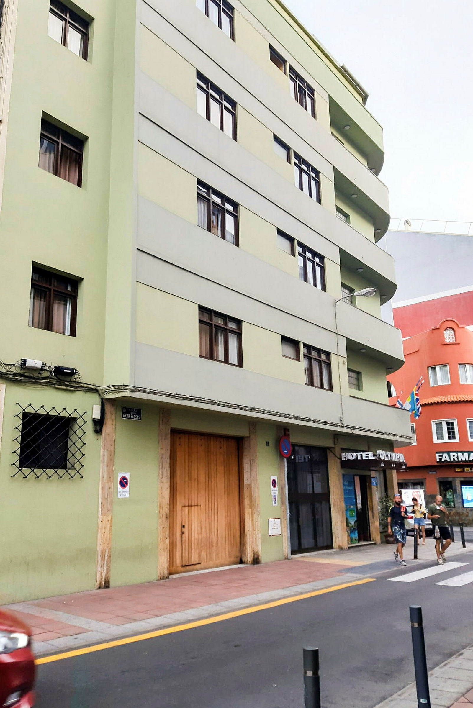 Grön byggnad med hotellskylt och trottoar framför. (AI-genererad text)