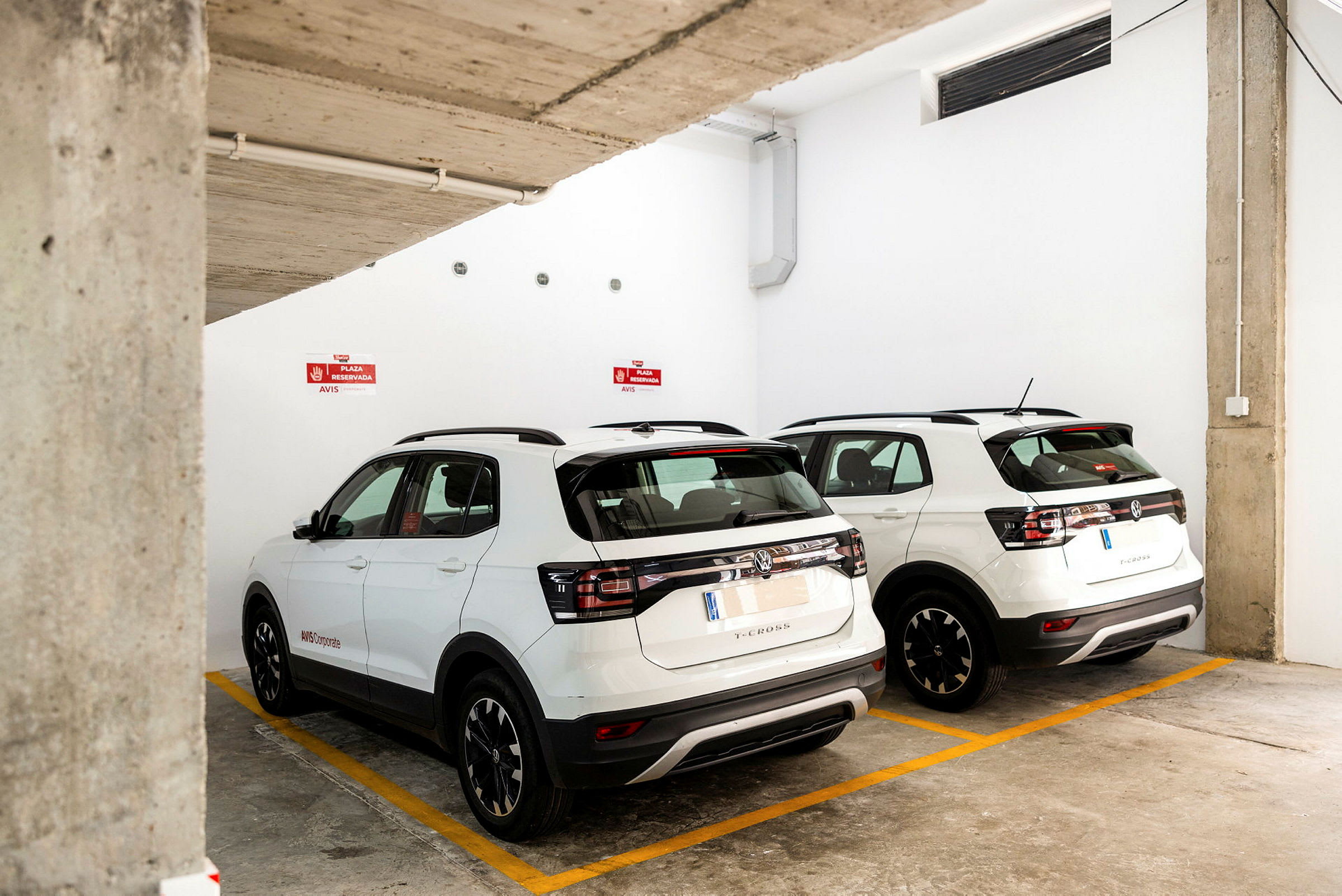 Två vita SUV-bilar parkerade i en underjordisk parkeringsplats. (AI-genererad text)