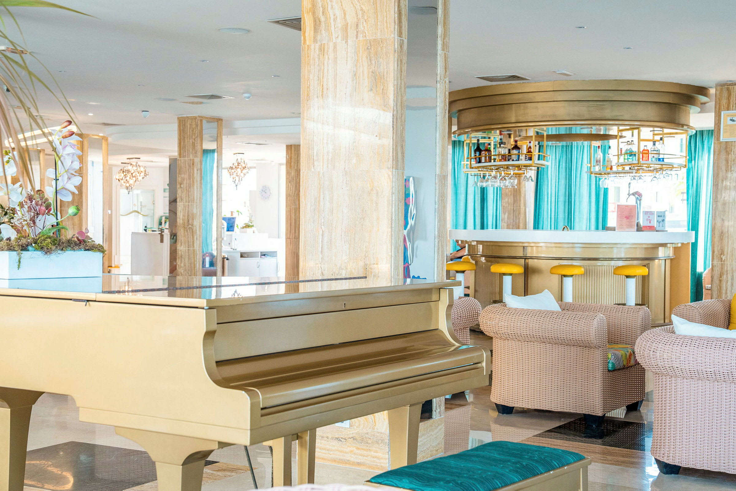 Ett elegant hotellutrymme med ett gyllene piano, bekväma sittgrupper och en modern bar i bakgrunden. (AI-genererad text)