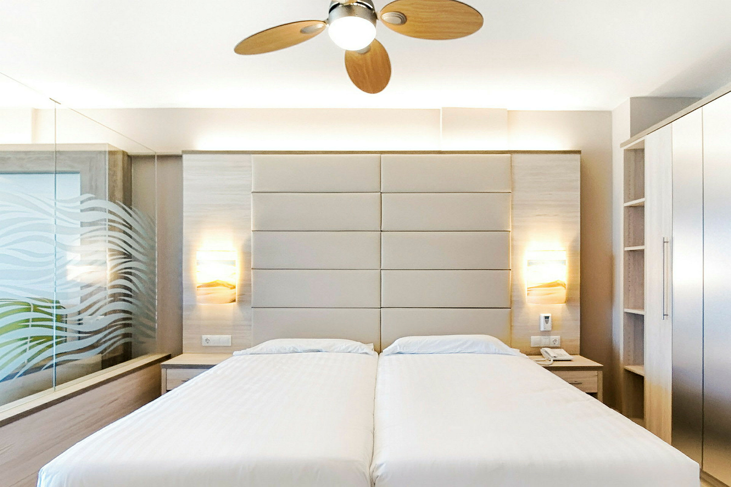 Hotellrum med två enkelsängar, modern inredning och takfläkt. (AI-genererad text)