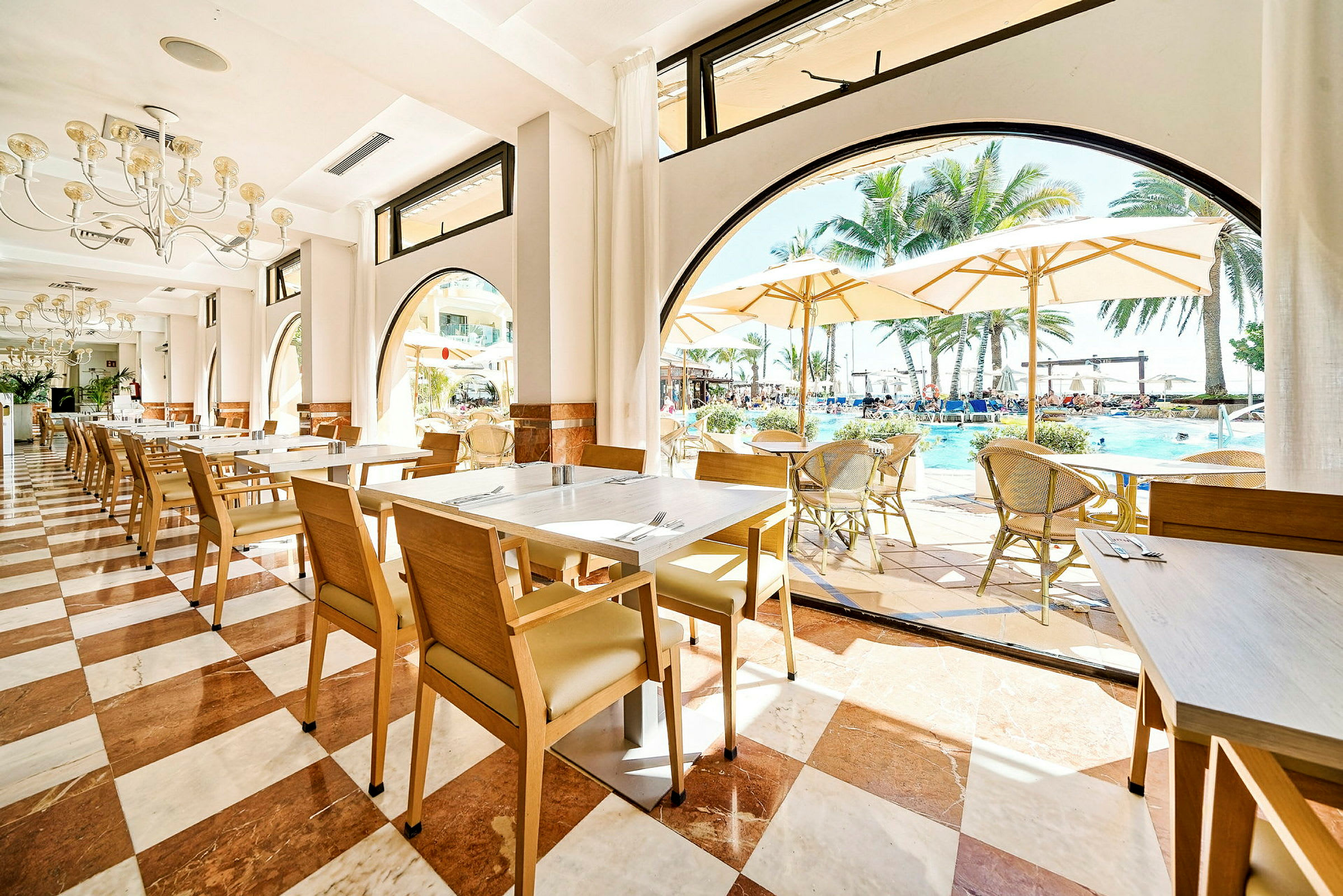 Bild av en restaurang med utsikt över en pool och palmträd. (AI-genererad text)