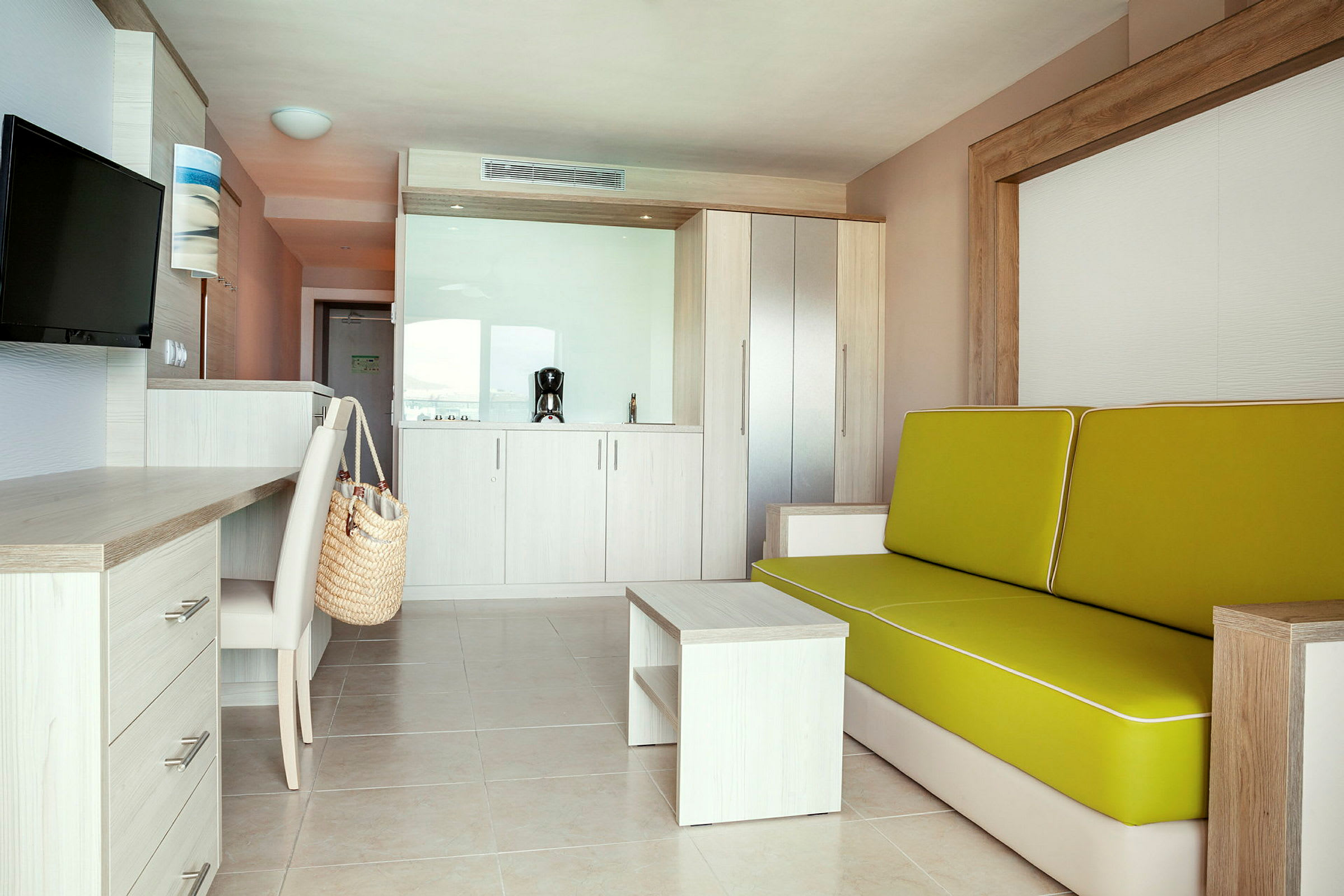 Modernt hotellrum med soffa, skrivbord och pentry. (AI-genererad text)