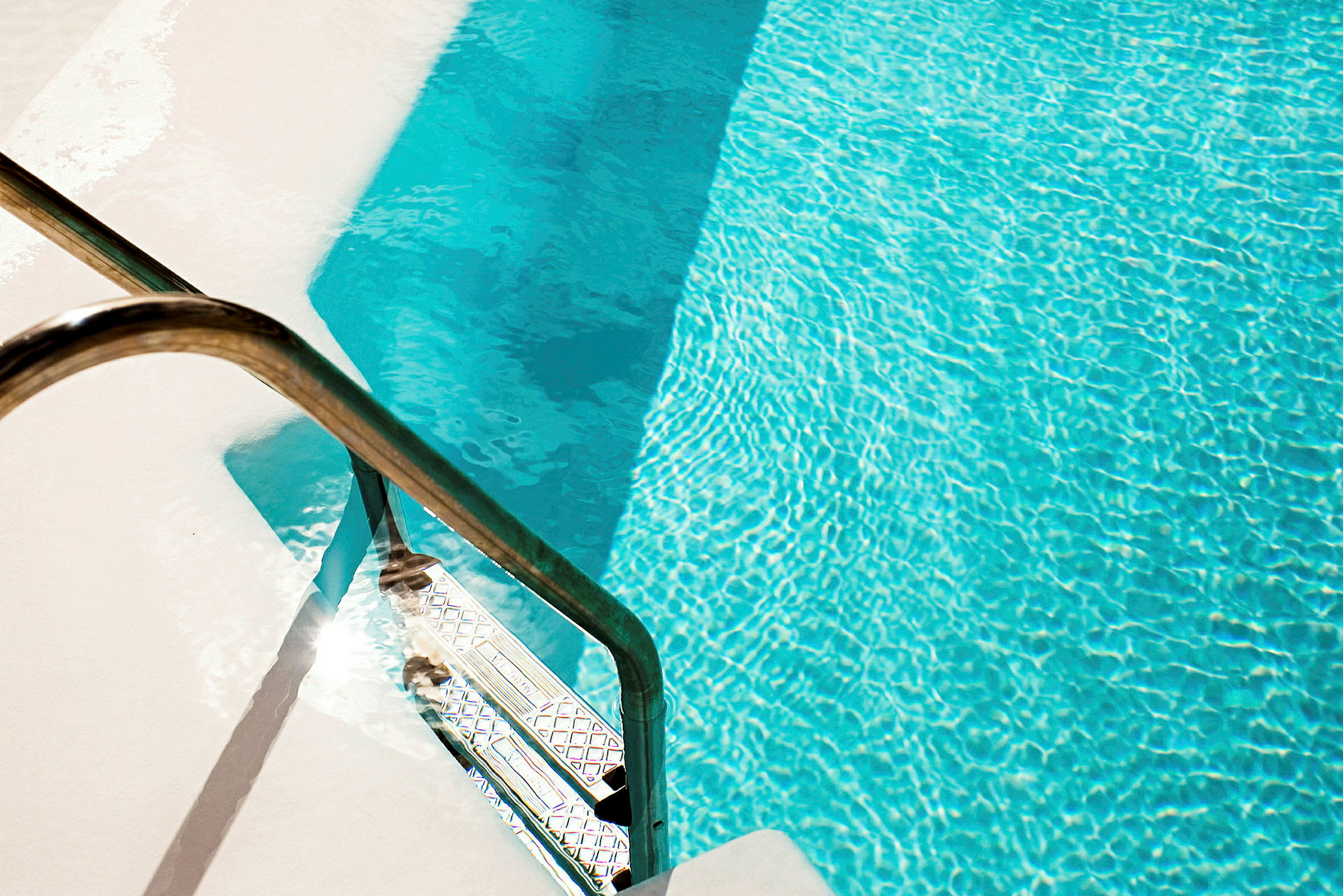 En swimmingpool med klart blått vatten och en metallstege. (AI-genererad text)