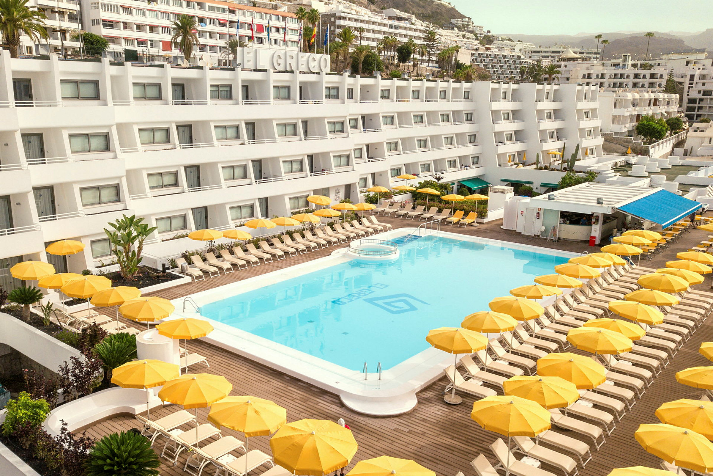 Hotell med pool och gula parasoller. (AI-genererad text)