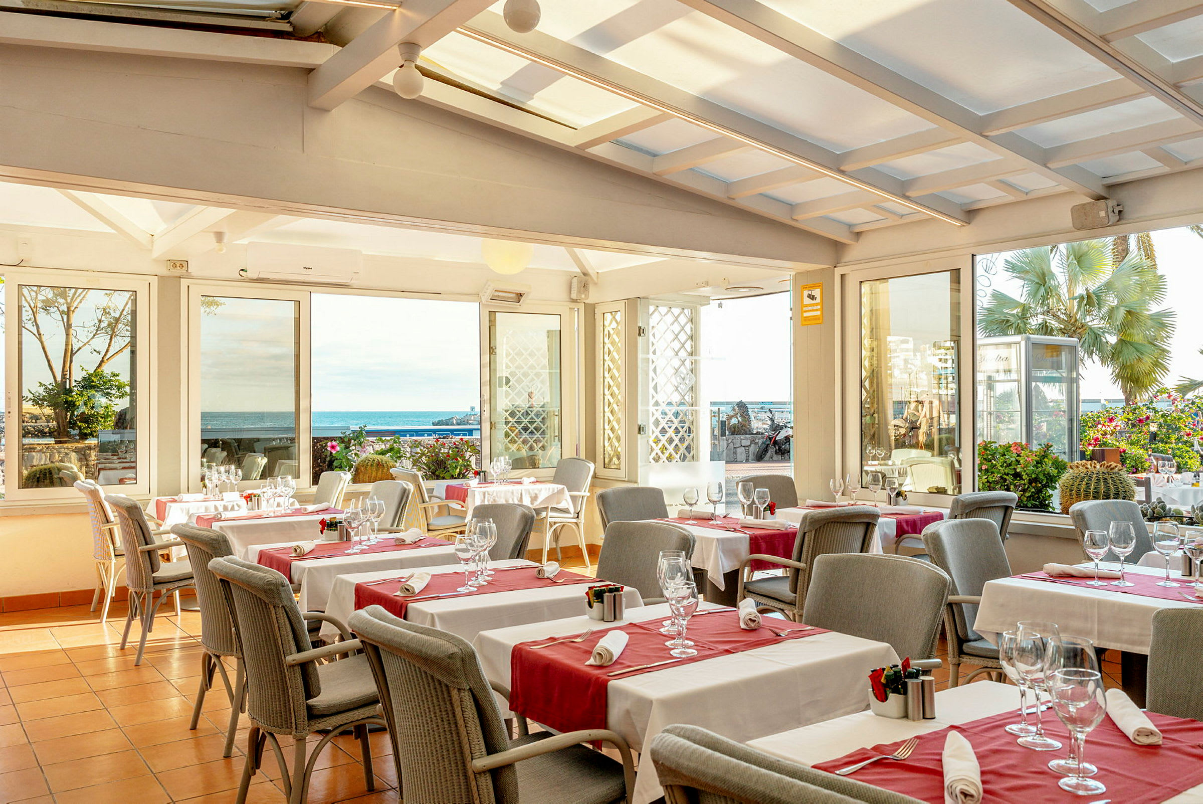 En restaurang med dukade bord och glas med utsikt mot havet. (AI-genererad text)