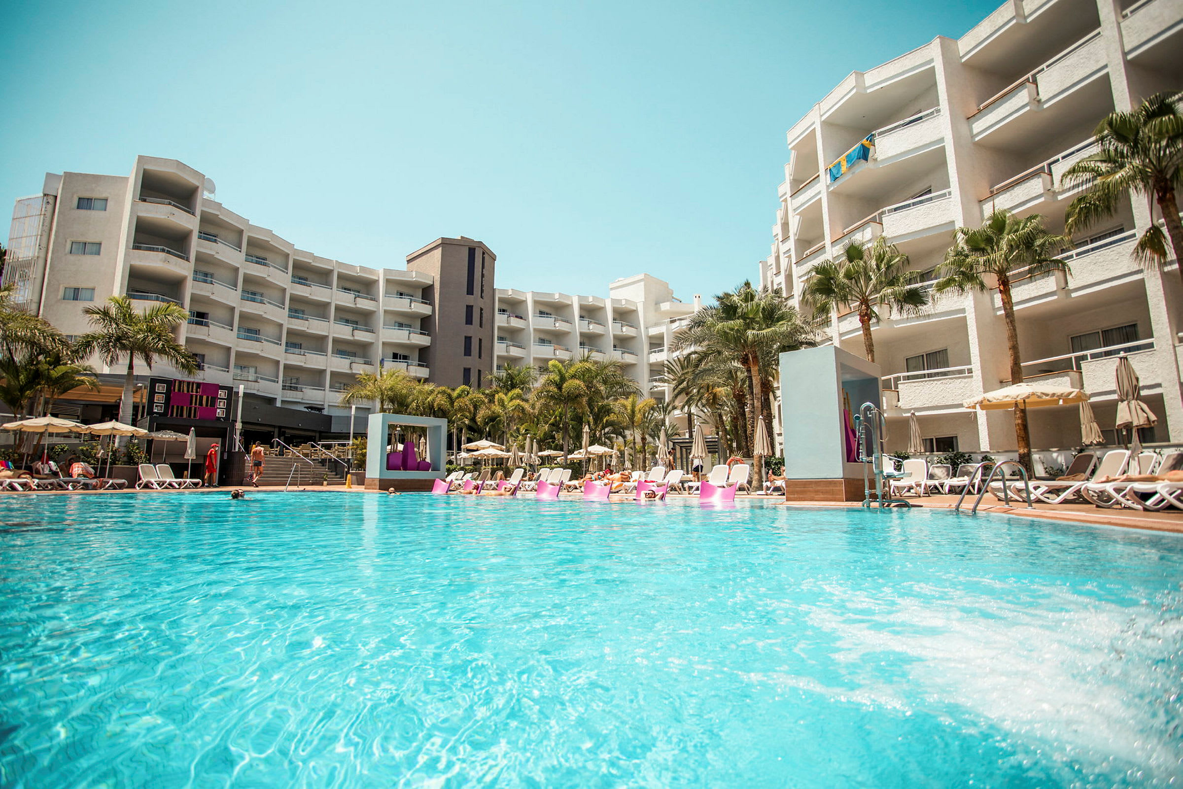 En hotellpool vid ett större byggnadskomplex. (AI-genererad text)