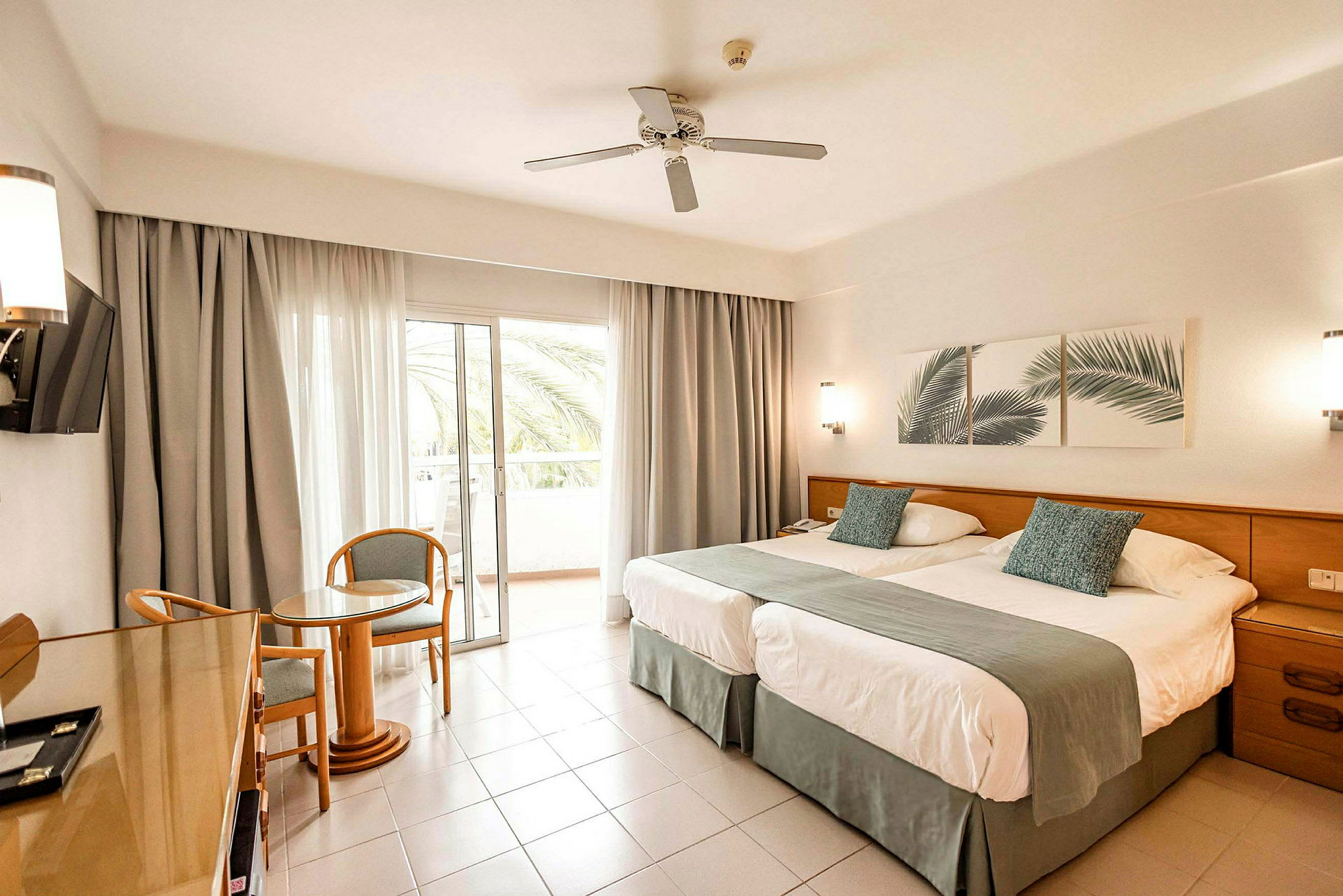 Hotellrum med två sängar, sittgrupp och balkong. (AI-genererad text)