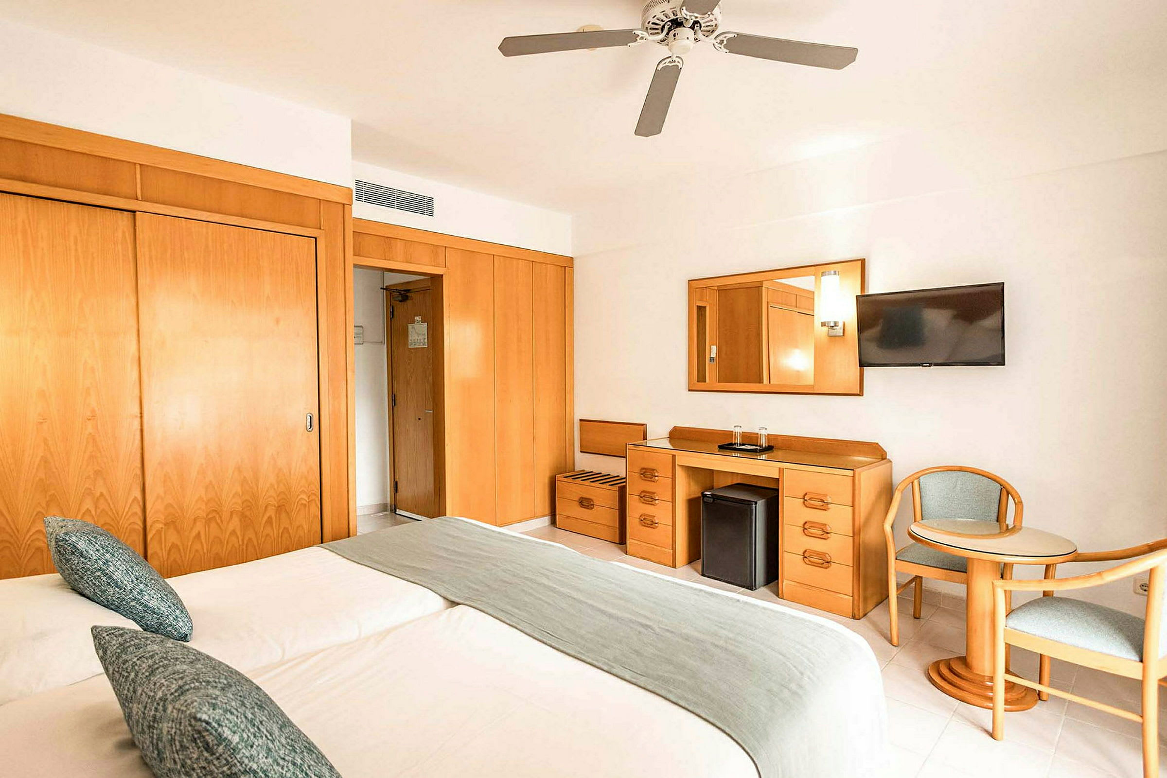 Hotellrum med två sängar, bord, stolar och förvaringsmöbler. (AI-genererad text)
