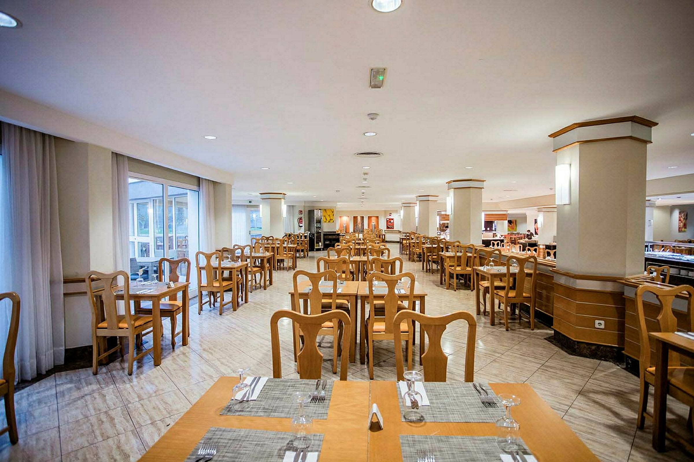 Restaurang med bord och stolar i trä samt dukar och glas. (AI-genererad text)