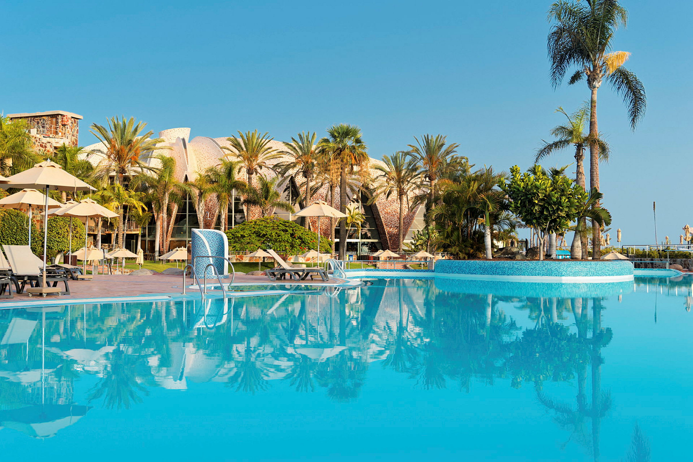 En pool med palmträd och solstolar på en turistort. (AI-genererad text)