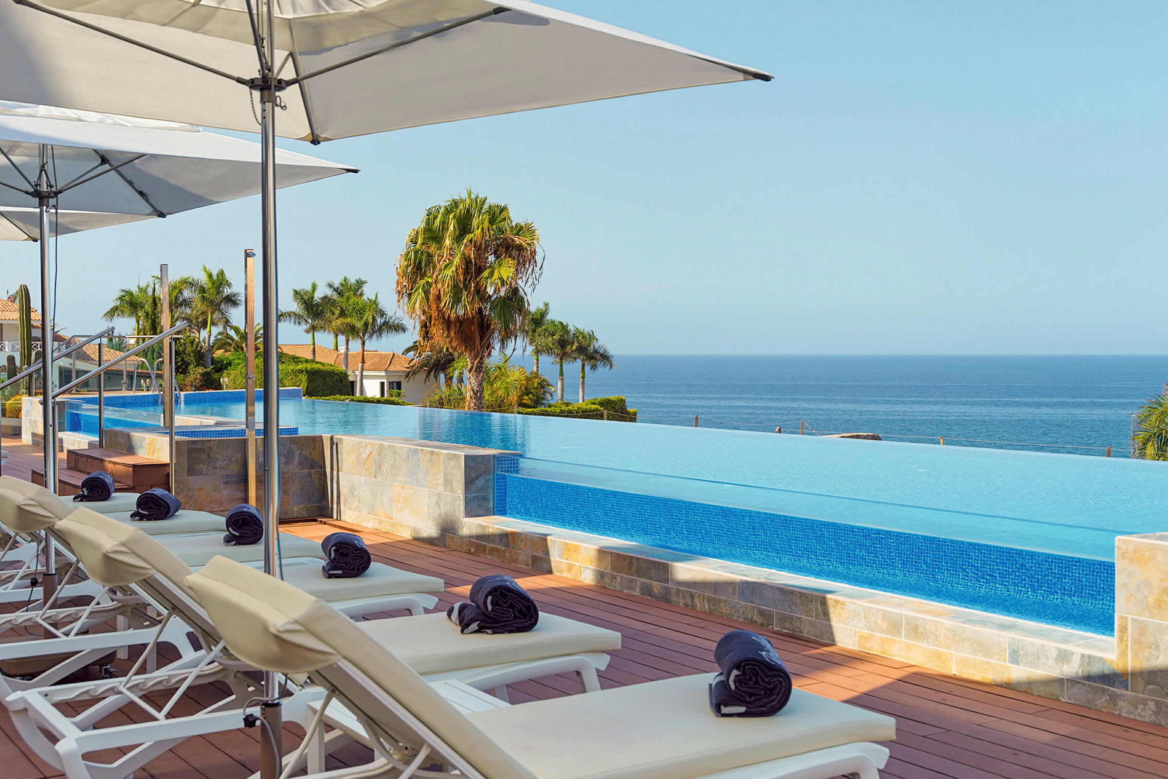 Solstolar och parasoller vid en infinitypool med utsikt över havet. (AI-genererad text)