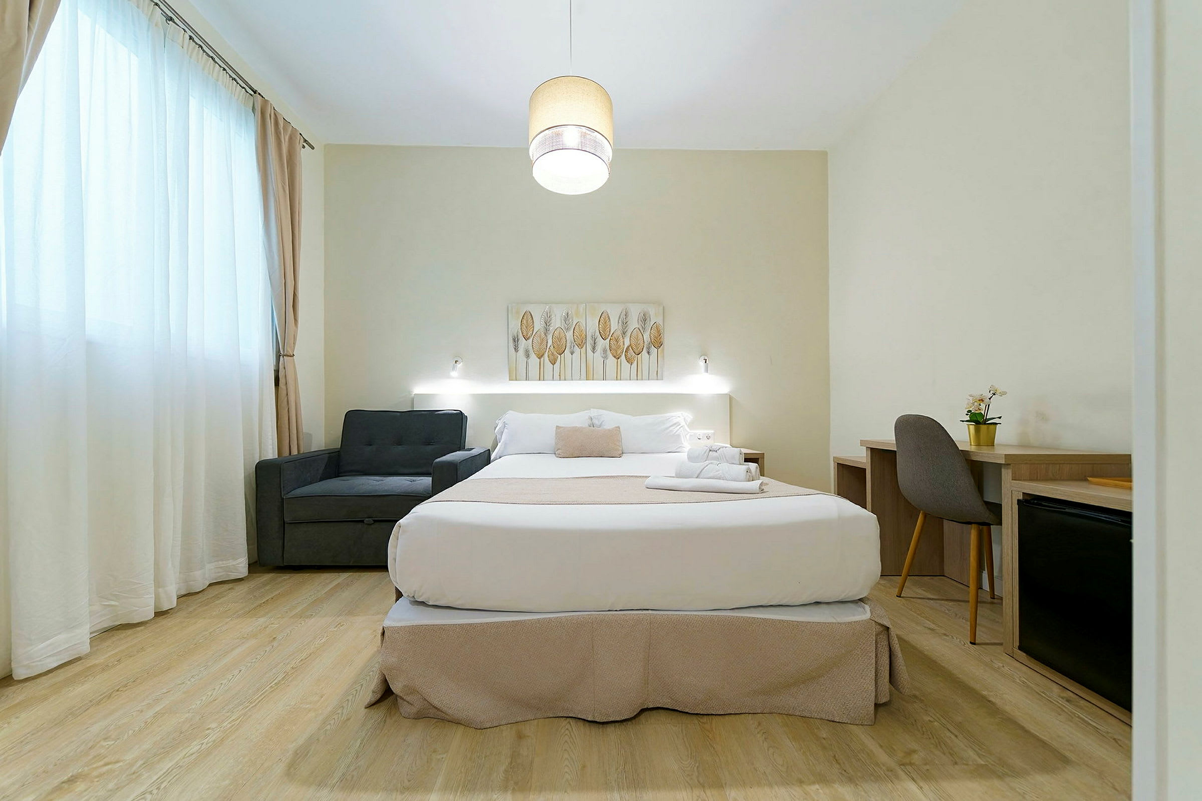 Ett hotellrum med en dubbelsäng, fåtölj och skrivbord. (AI-genererad text)